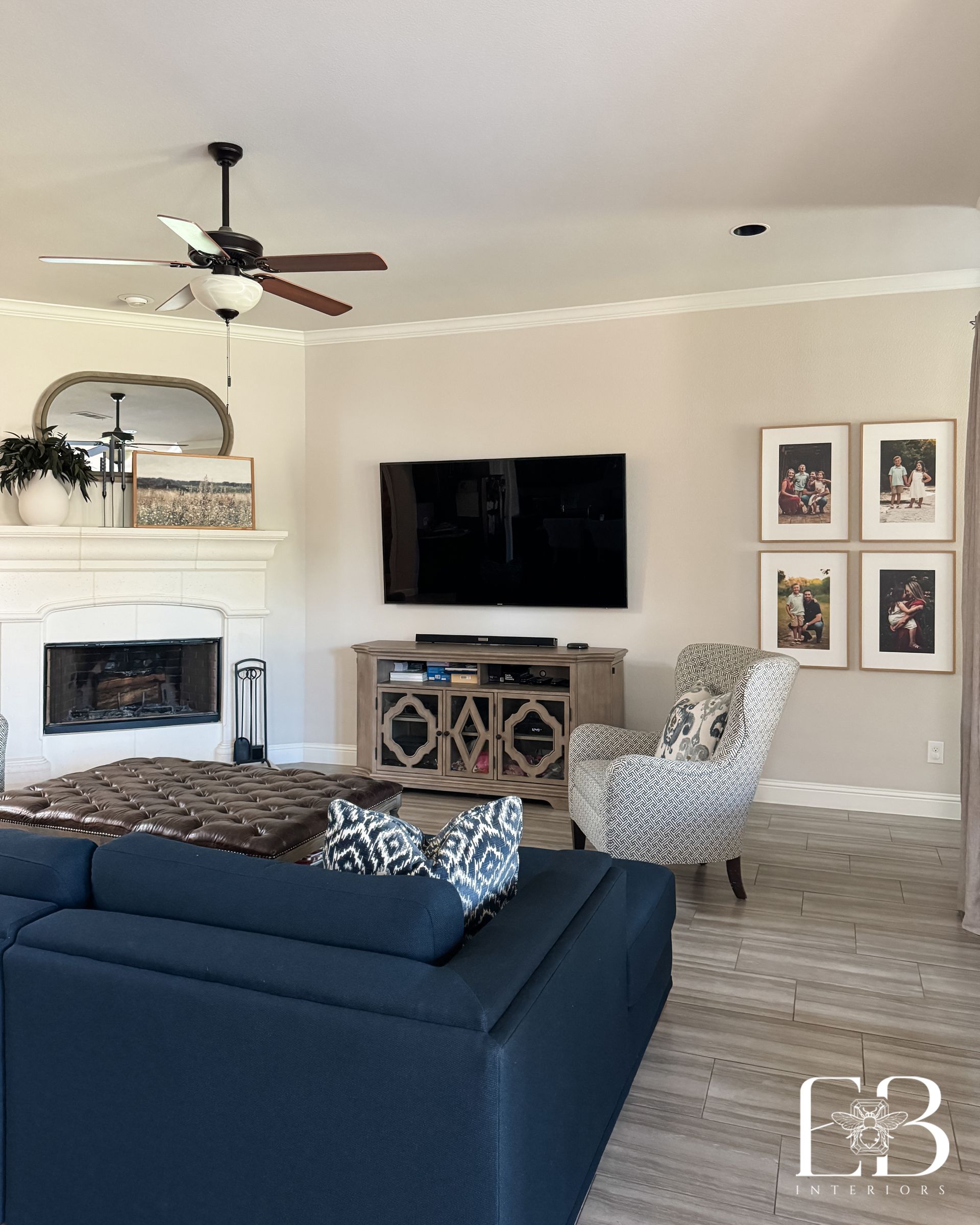 Living area with corner fireplace, navy sectional, and galley wall designed by Emerald Bee Interiors for Spanish Oak Trail.
