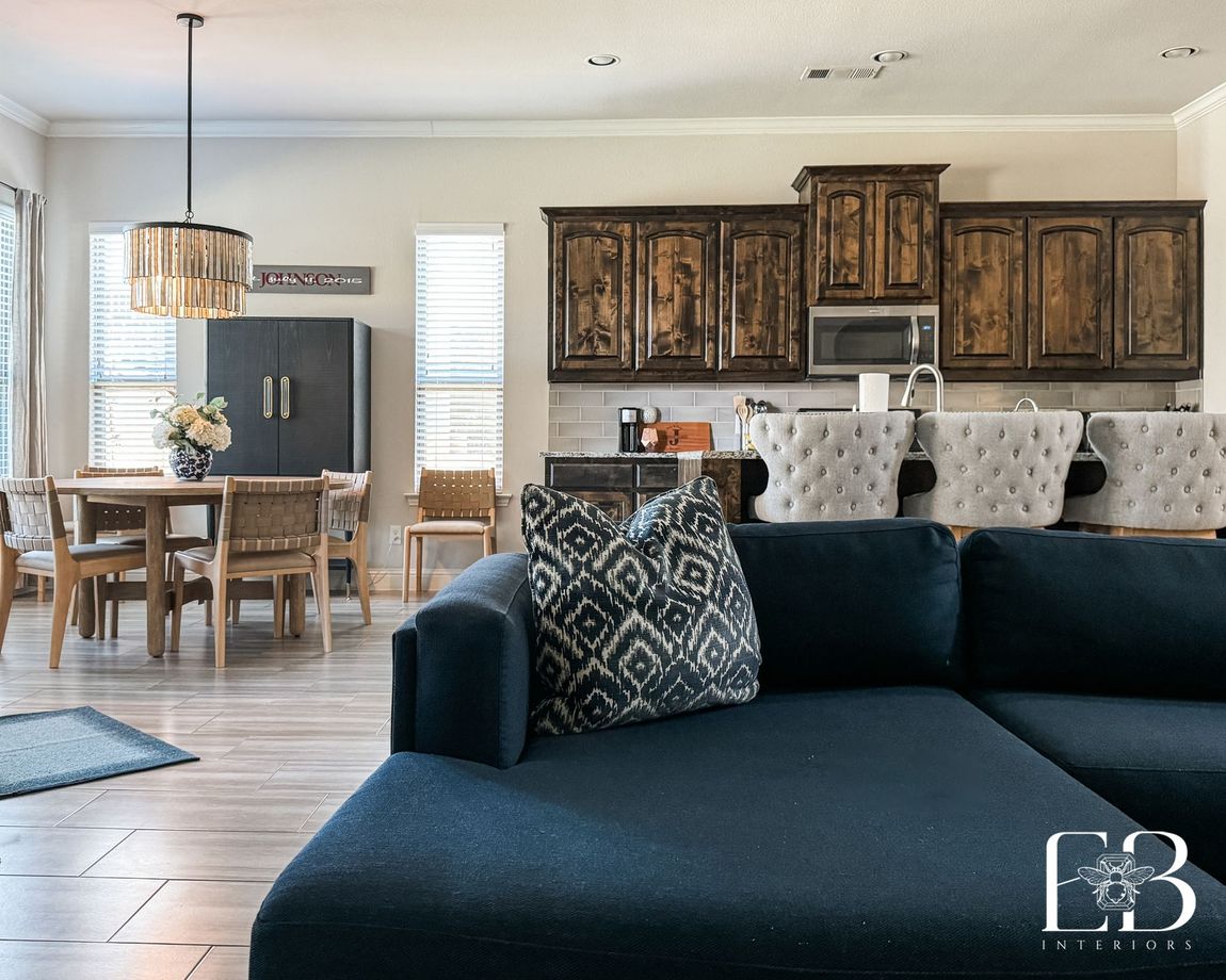 Open kitchen and dining space with warm wood cabinetry and updated furnishings by Emerald Bee Interiors.