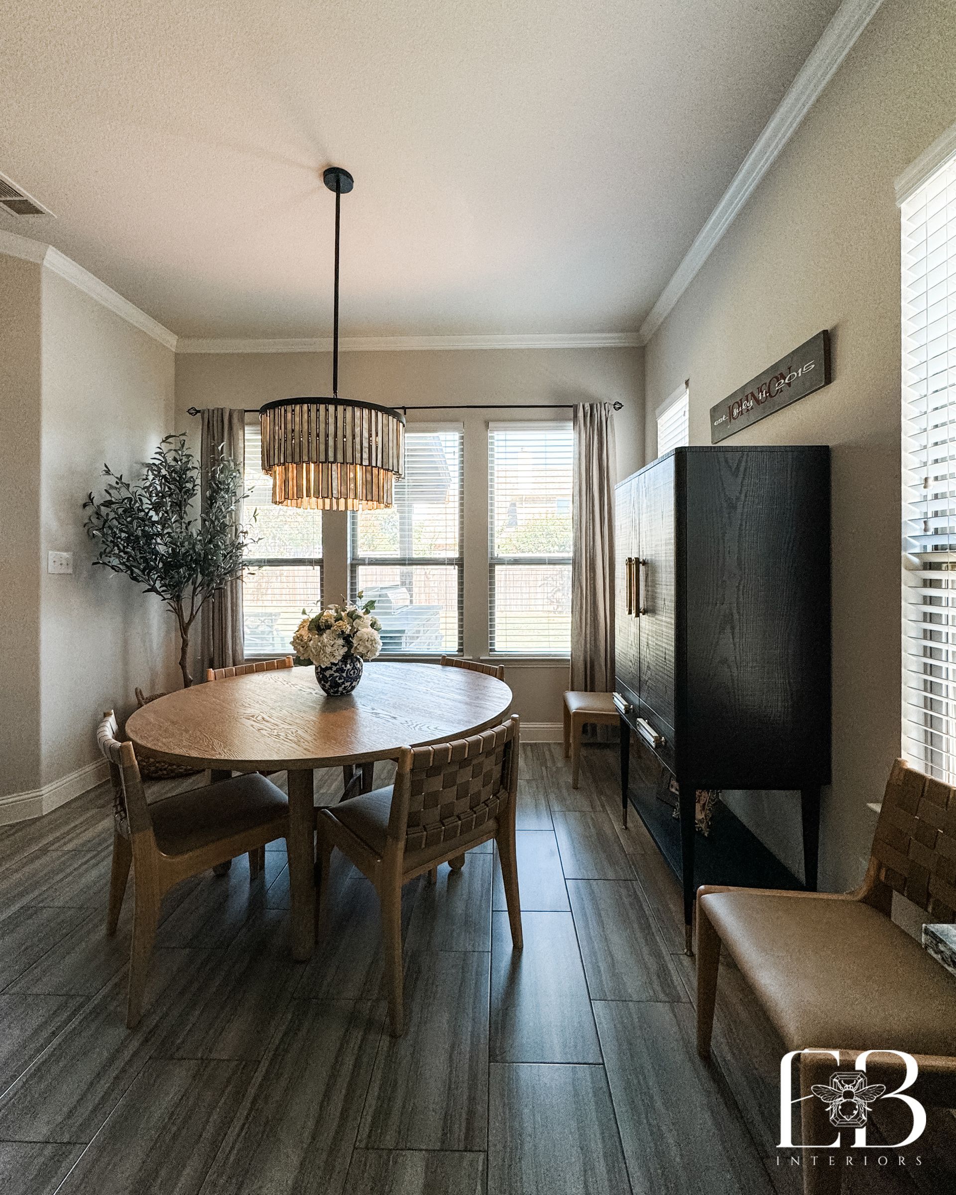 Dining area with round wood table, woven chairs, and drum pendant light by Emerald Bee Interiors for Spanish Oak Trail.