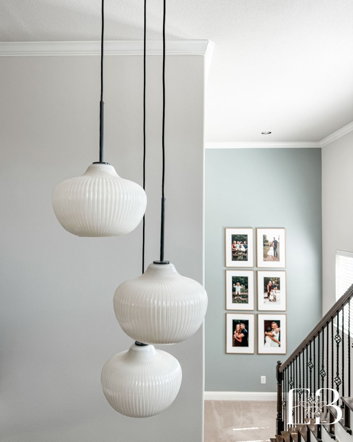 Modern staircase with black iron railing and tiered globe pendants in the Spanish Oak Trail home by Emerald Bee Interiors.