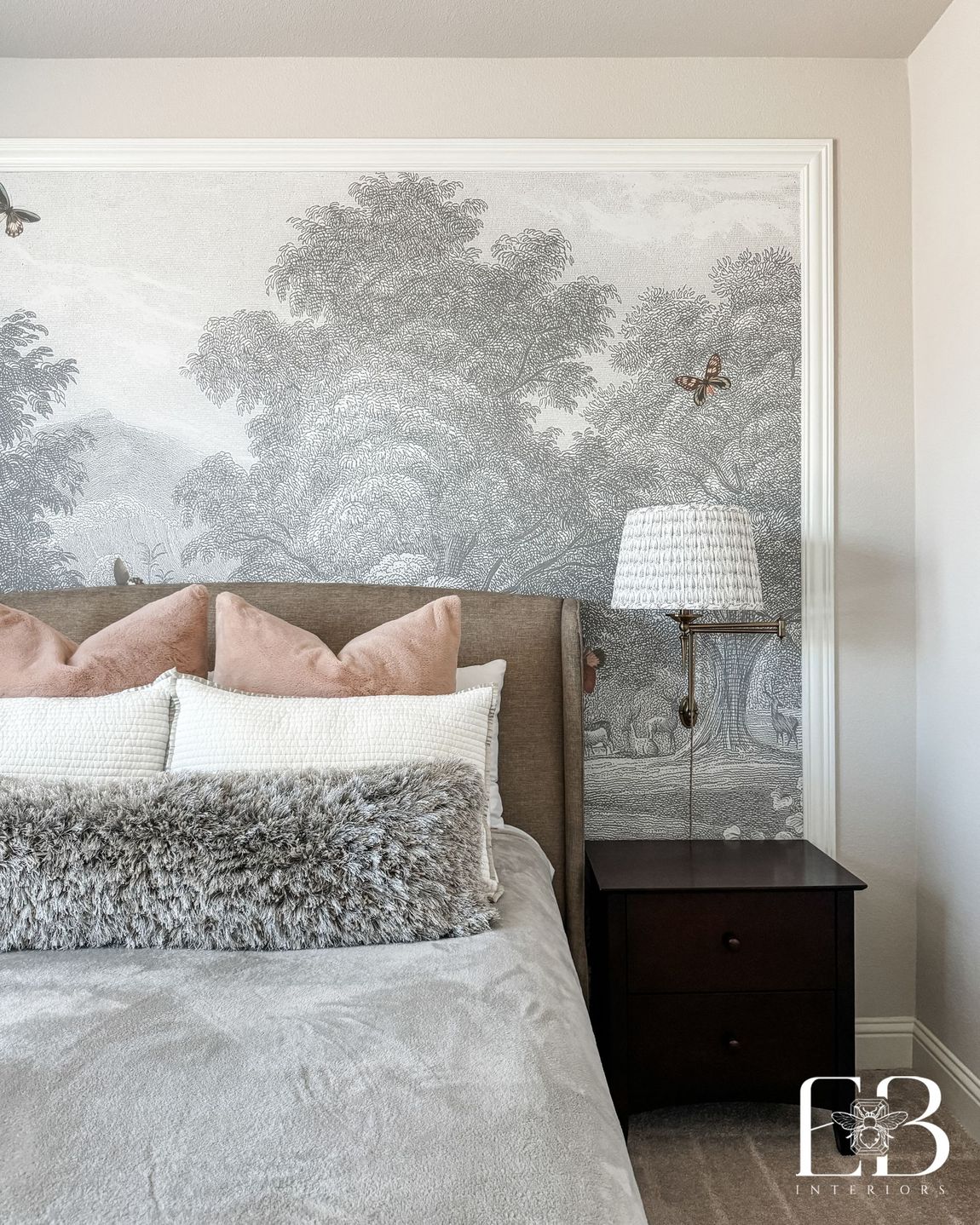 Guest bedroom with tonal mural wallpaper, velvet headboard, and layered neutral bedding designed by Emerald Bee Interiors.