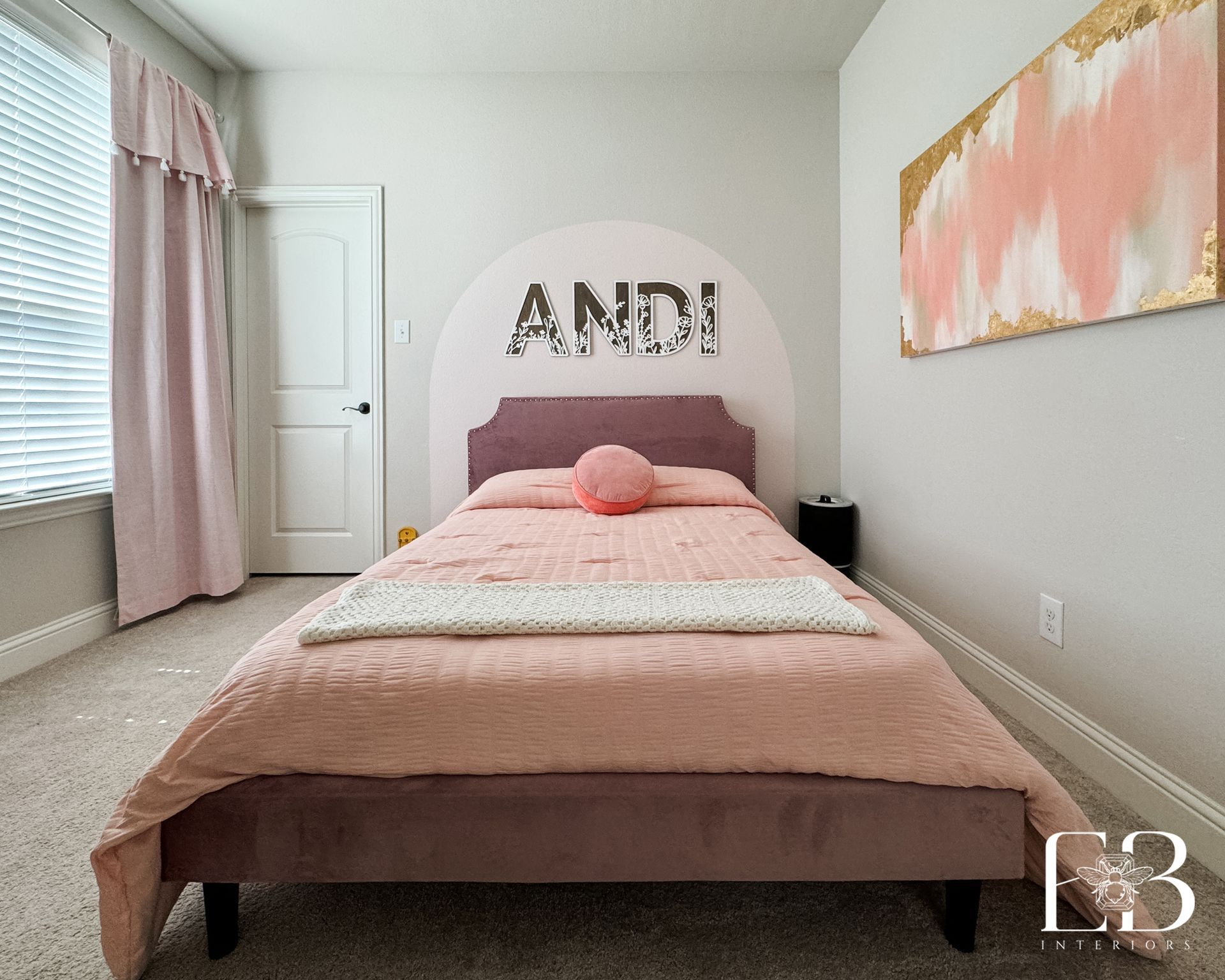 Girls’ bedroom with pink arched wall, name accent, and blush velvet bed designed by Emerald Bee Interiors.
