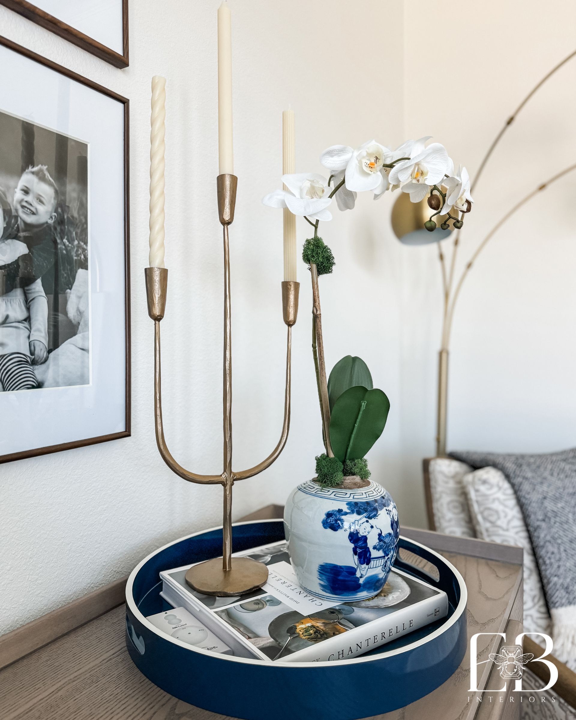 Detail vignette of gold candlesticks, blue chinoiserie vase, and orchid arrangement styled by Emerald Bee Interiors.