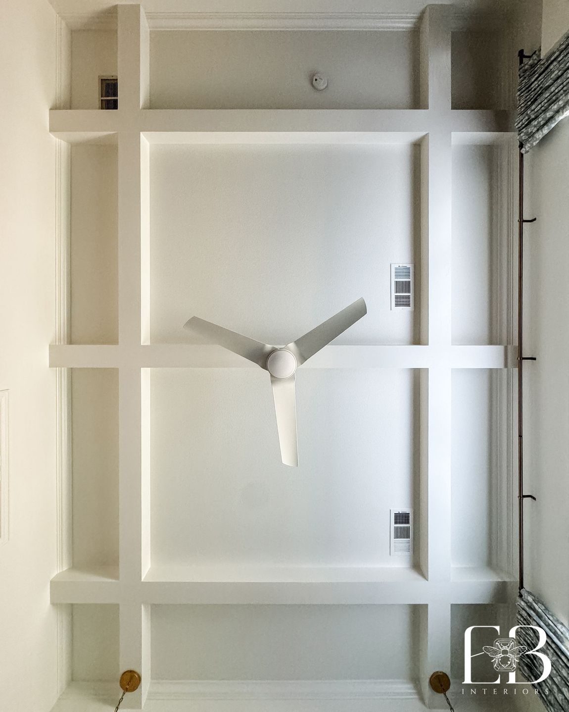 Coffered ceiling and modern white fan in the Spanish Oak Trail primary bedroom by Emerald Bee Interiors.