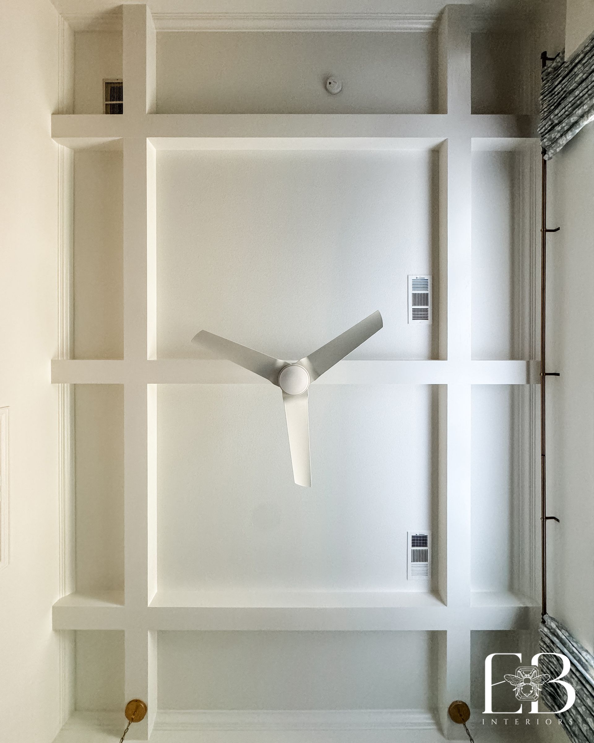 Coffered ceiling and modern white fan in the Spanish Oak Trail primary bedroom by Emerald Bee Interiors.