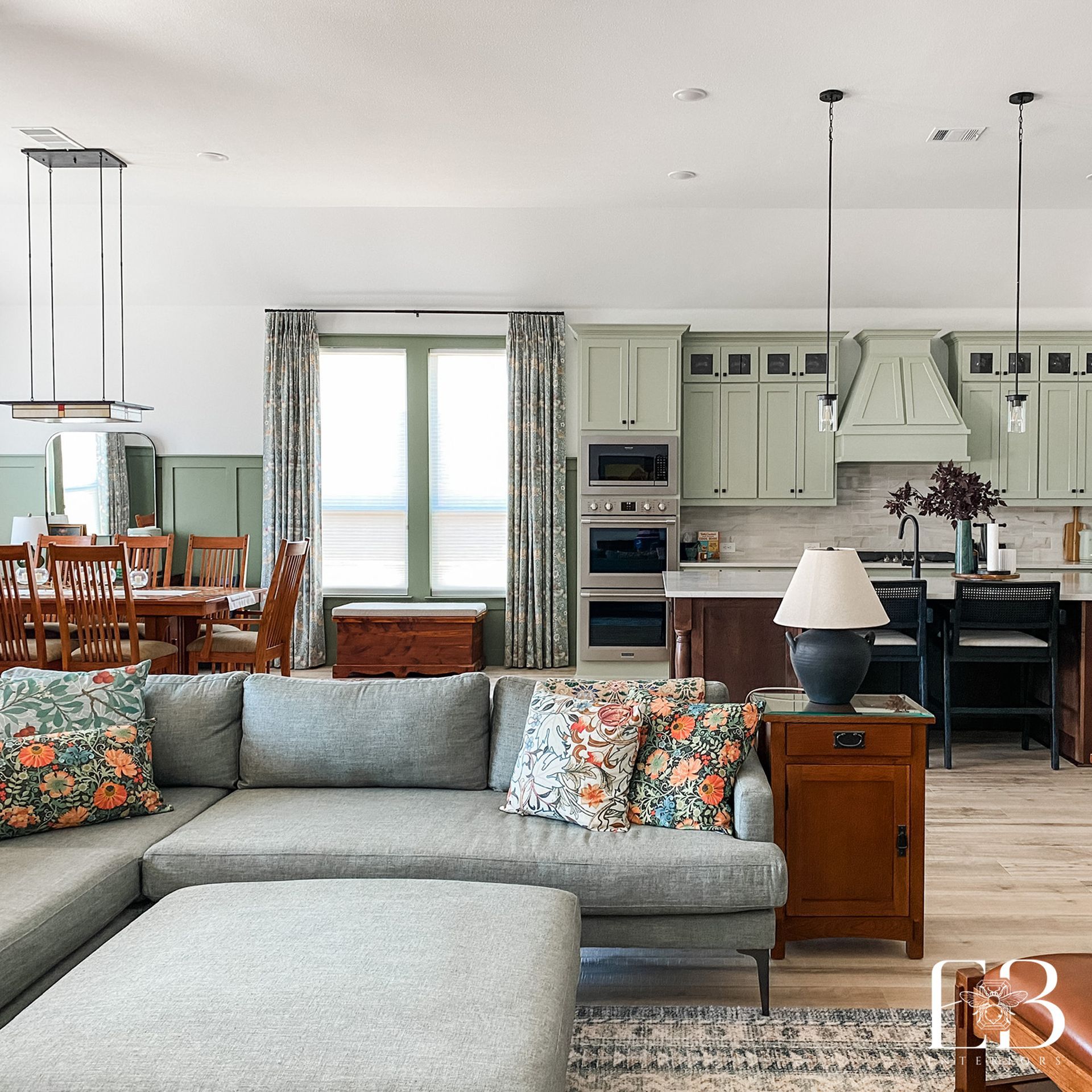 Spacious open-concept living space with gray sectional sofa, kitchen with green cabinets, and dining area.