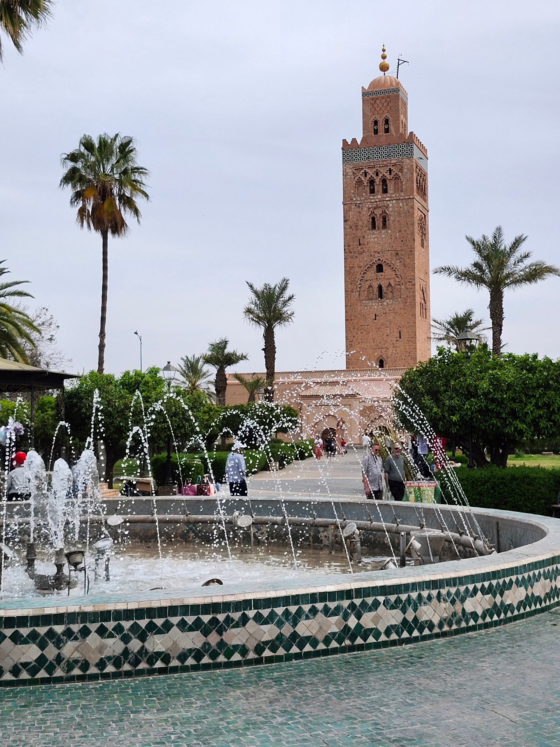 A fountain with a clock tower in the background