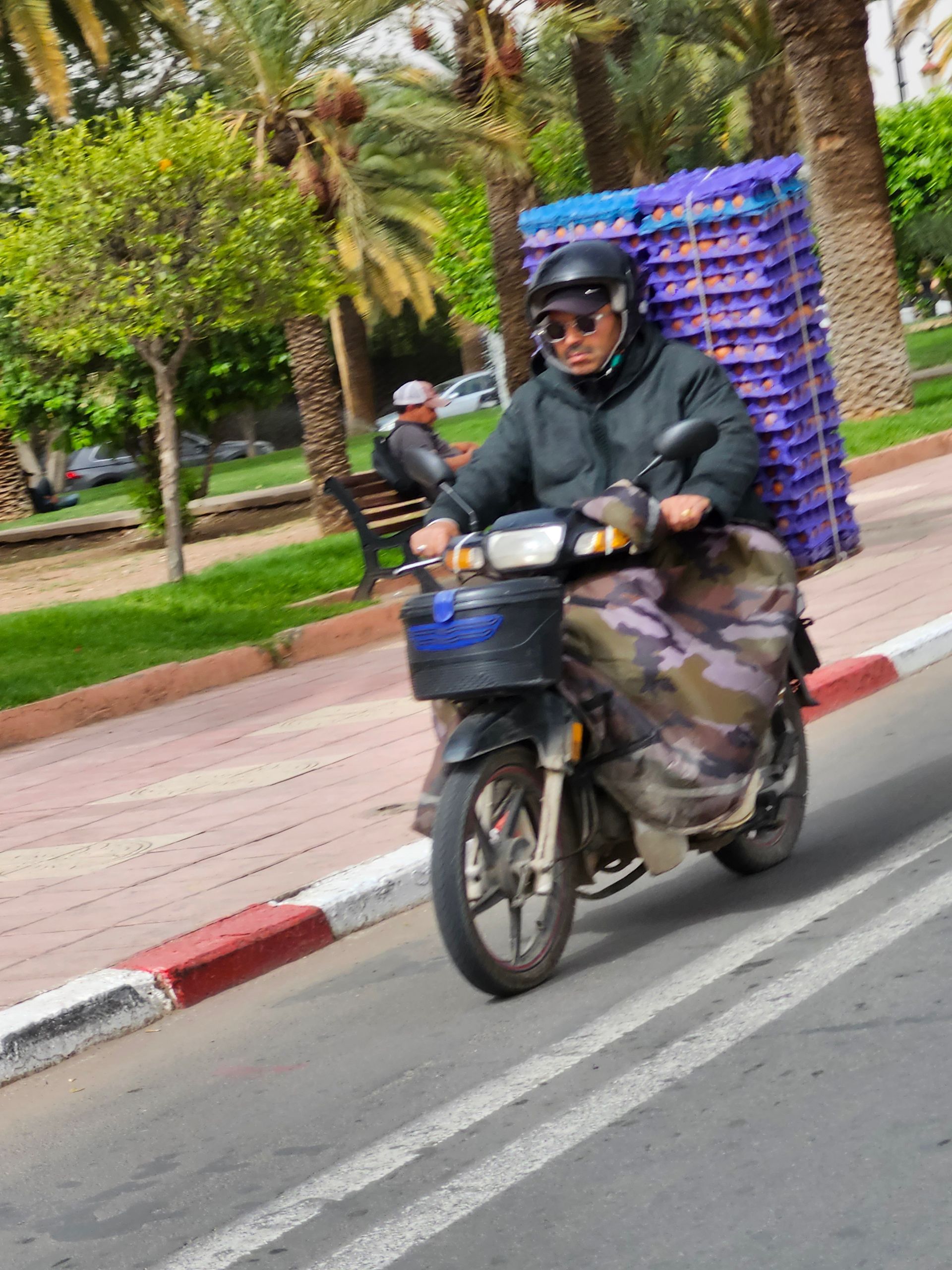 A man is riding a motorcycle with a basket on the back