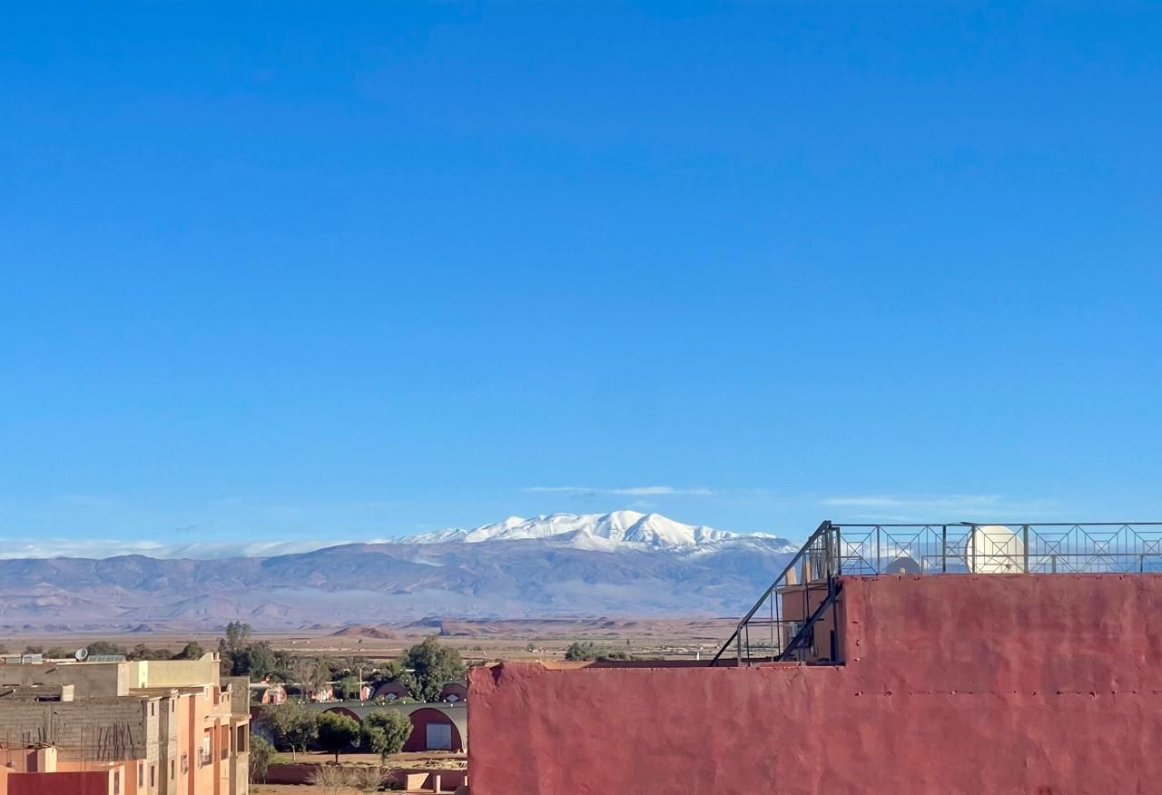 A red building with a balcony overlooking a snowy mountain range.