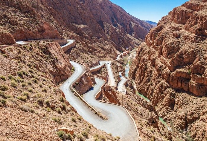 A road in the middle of a canyon with mountains in the background