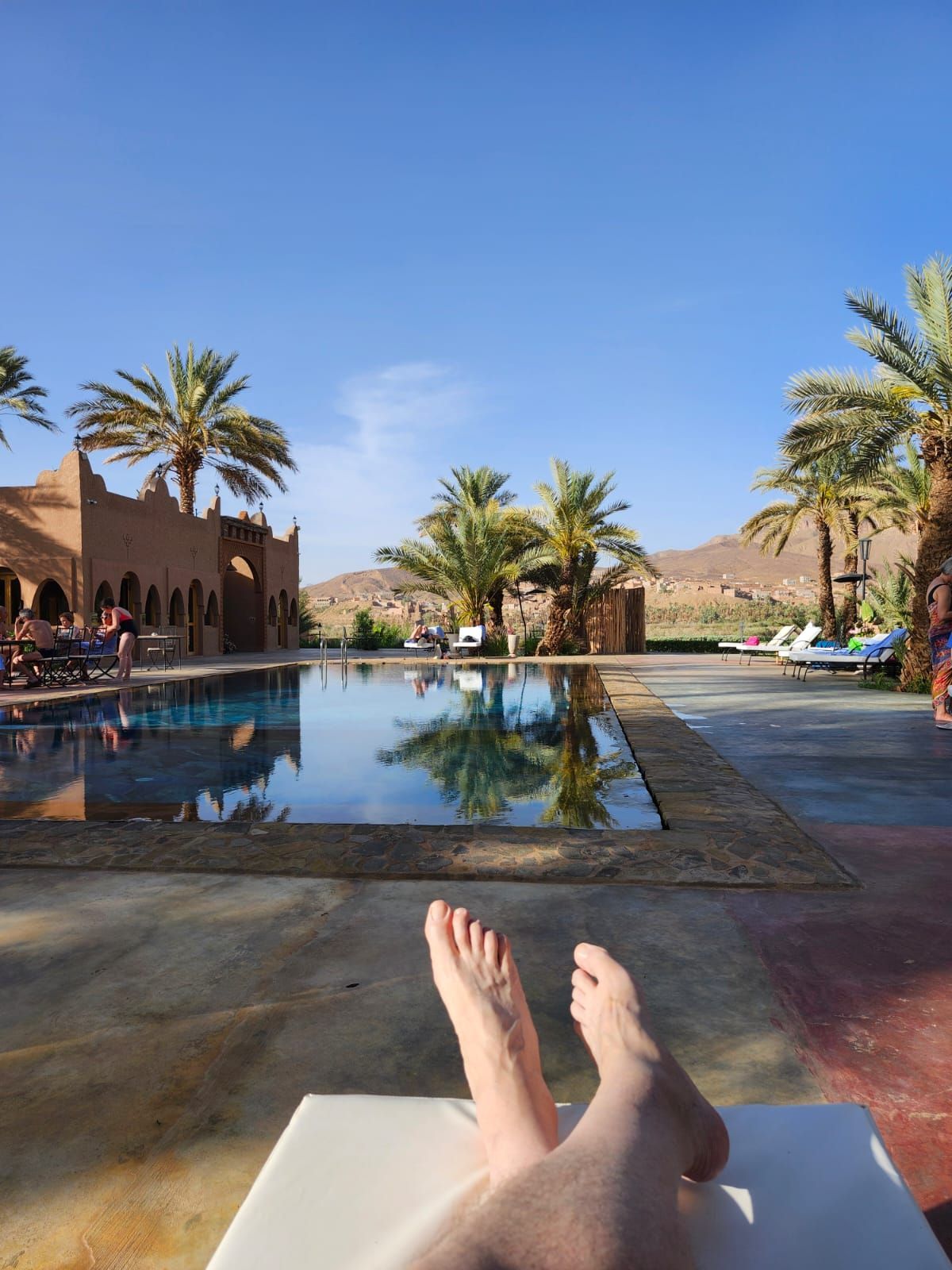A person is laying on a lounge chair in front of a swimming pool.