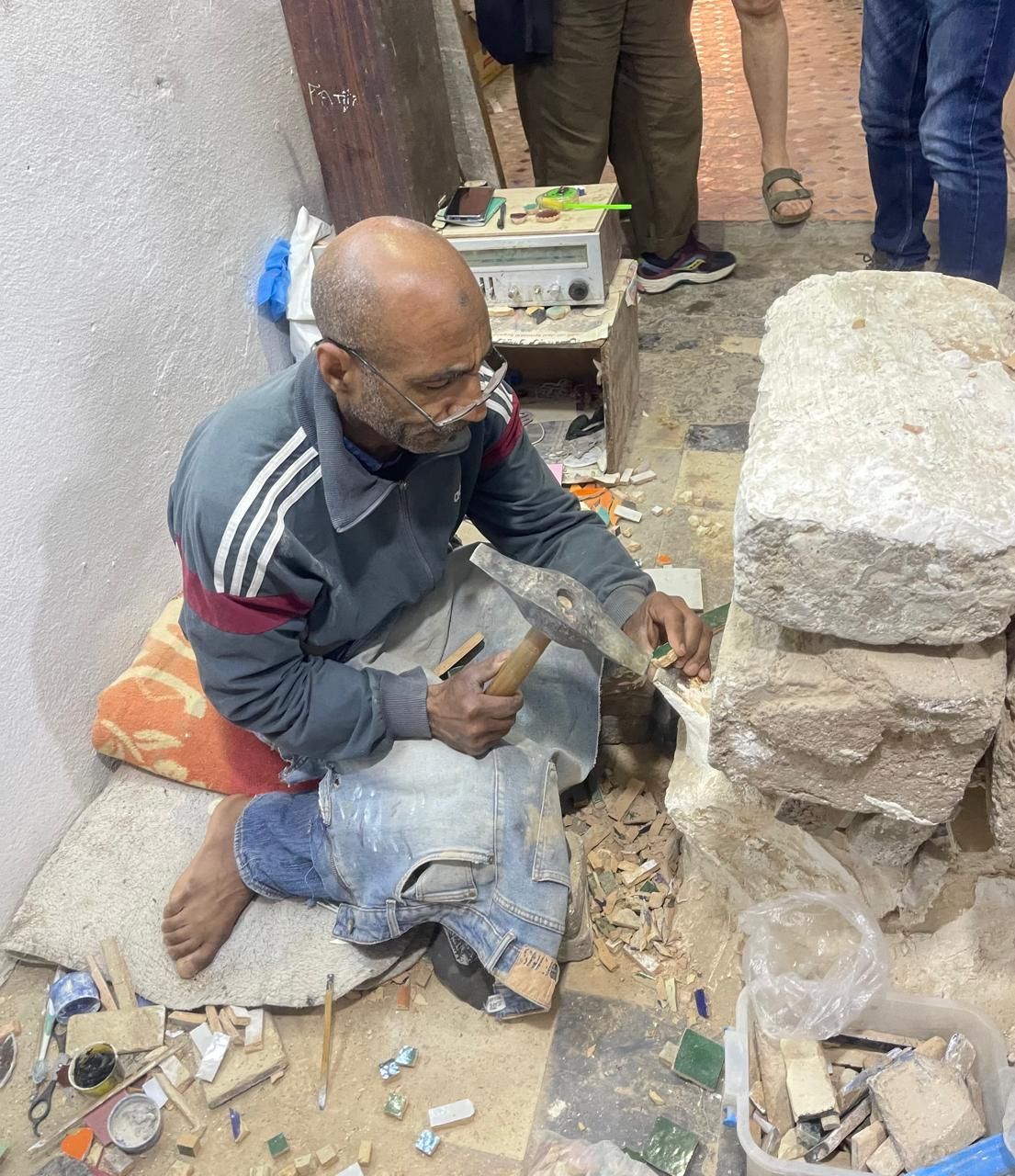 A man is kneeling on the floor holding a hammer.