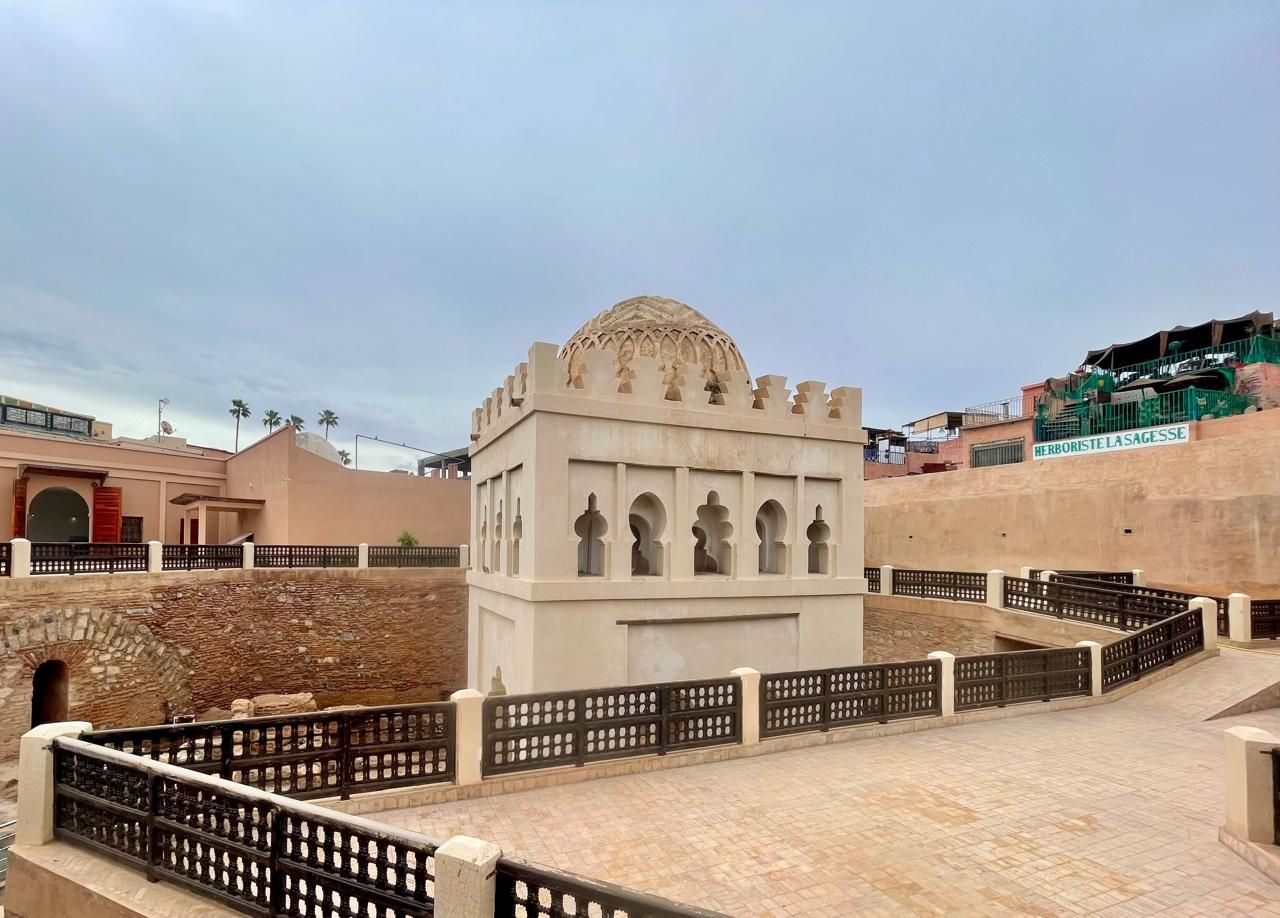 A white building with a fence around it is surrounded by a brick wall.