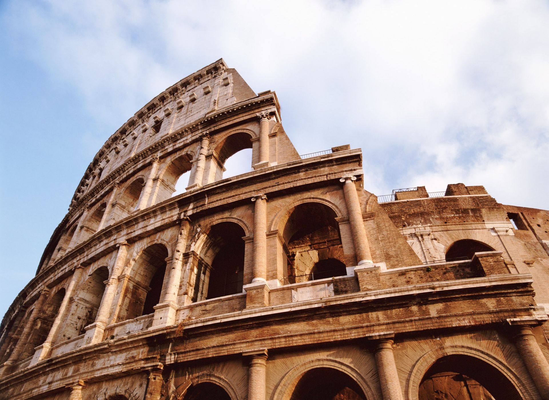 Colosseum in Rome, Italy, ancient amphitheater, crumbling facade, blue sky.