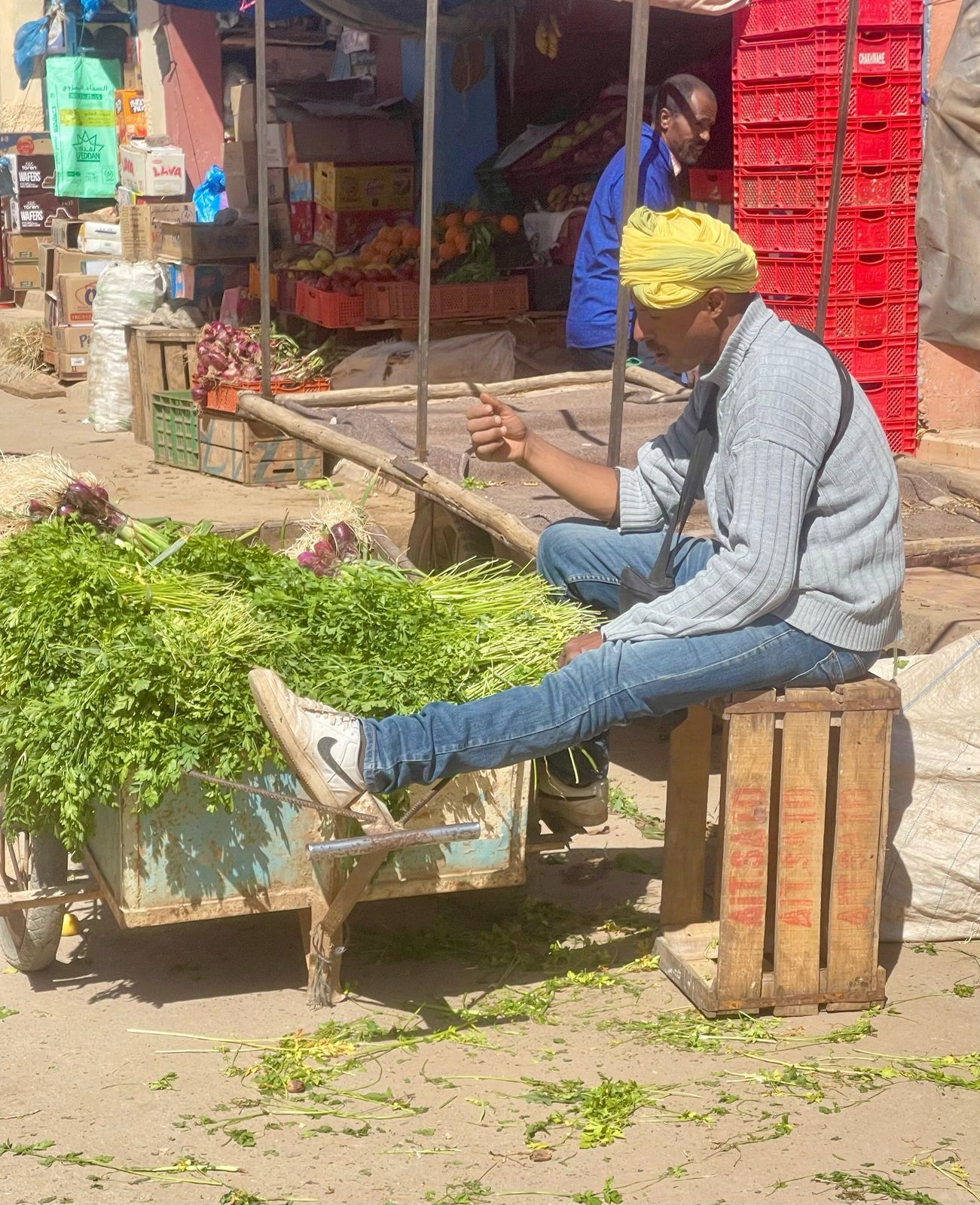 A man is sitting on a wooden box with his legs crossed