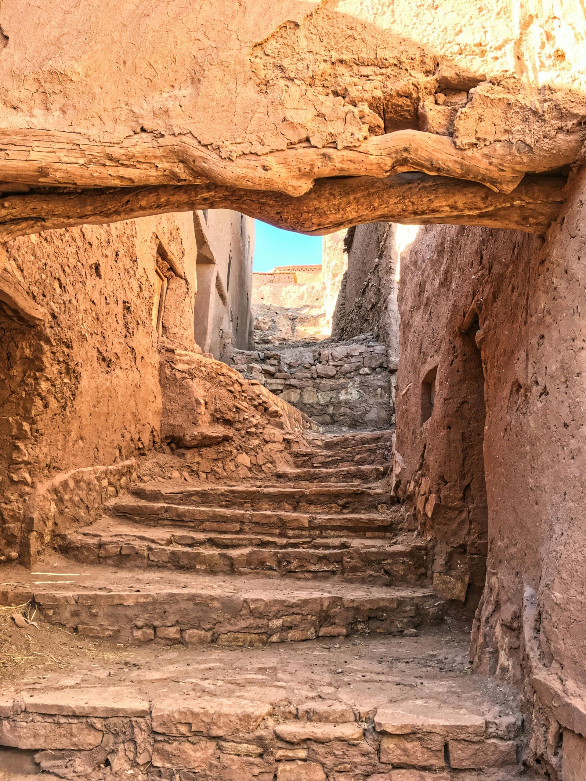 A stone bridge over a narrow alleyway with stairs leading up to it.