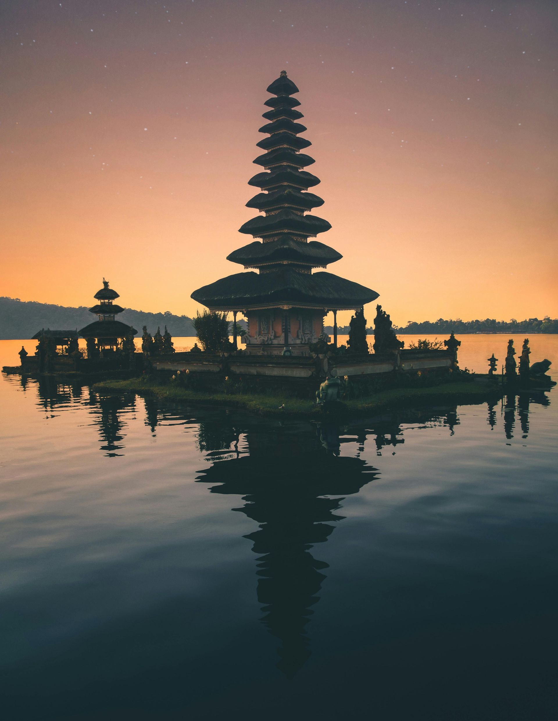 A Balinese temple in the middle of a lake at sunset