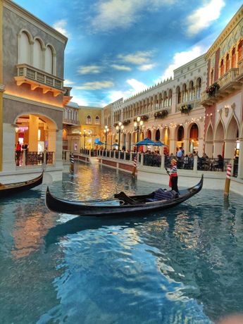 A man is riding a gondola down a canal in Venice, Italy.