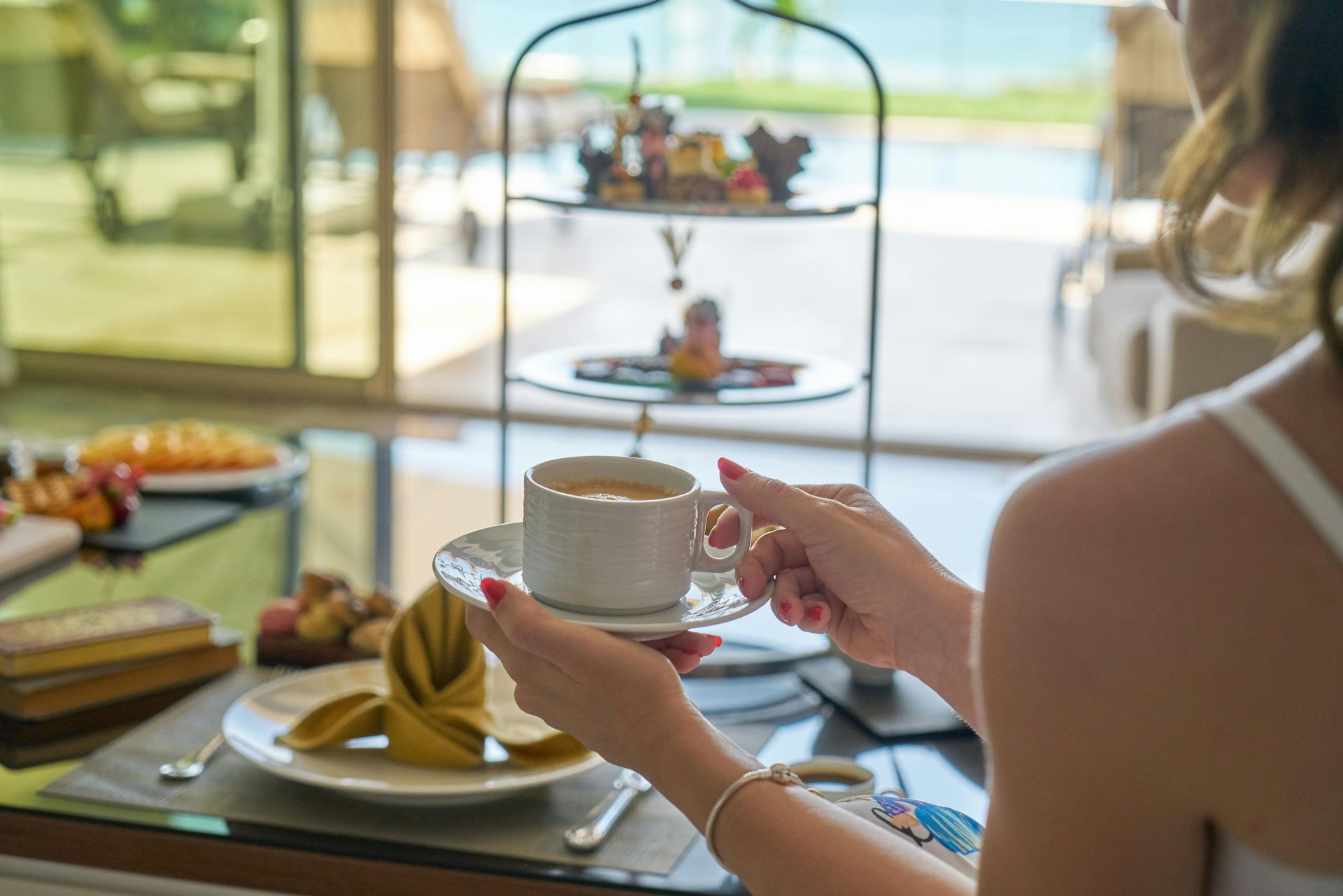 A woman is sitting at a table holding a cup of coffee.
