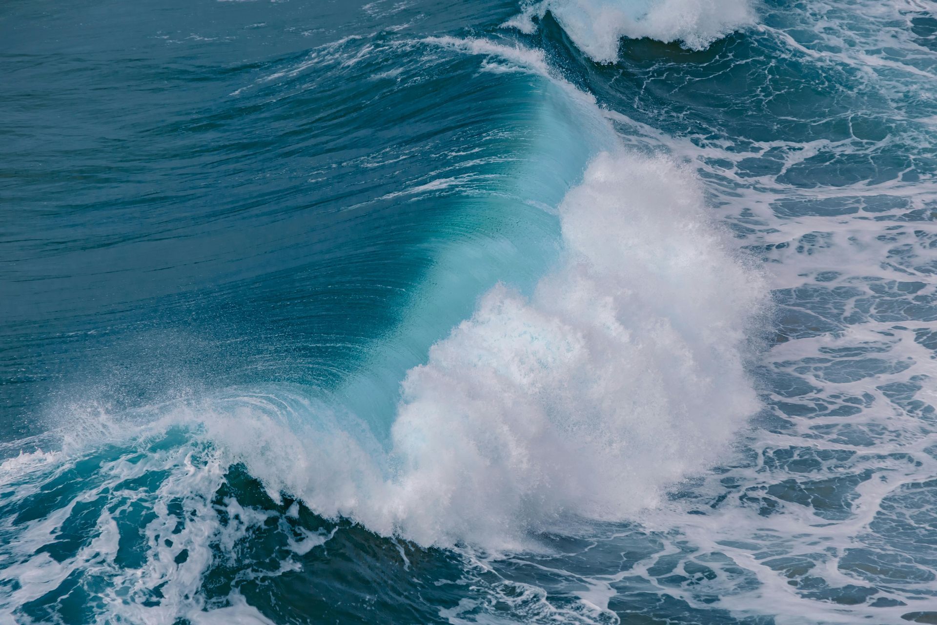 Crashing ocean wave, teal water and white foam.