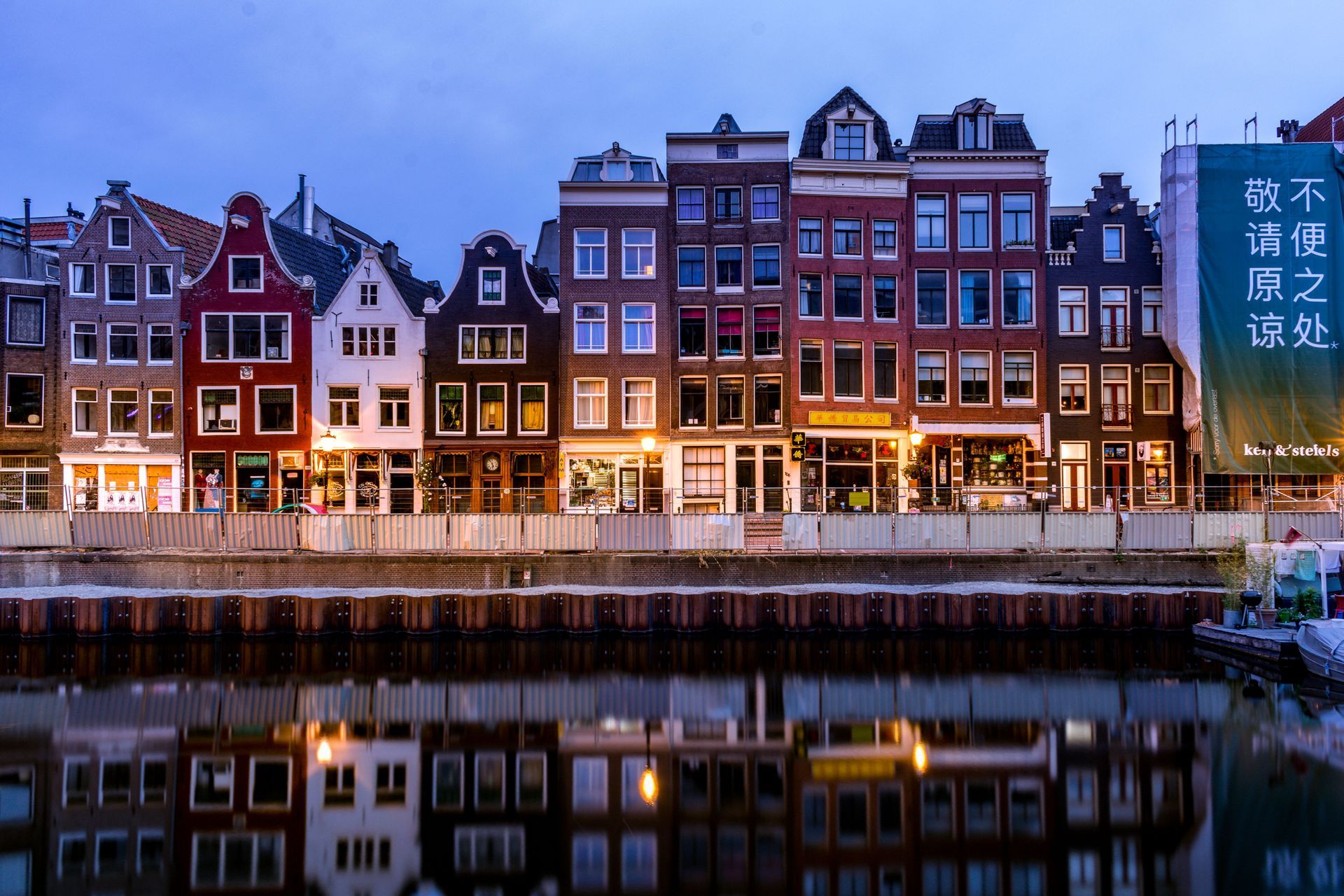 Canal in Amsterdam lined with buildings, bicycles on a bridge, and yellow tulips in the foreground.
