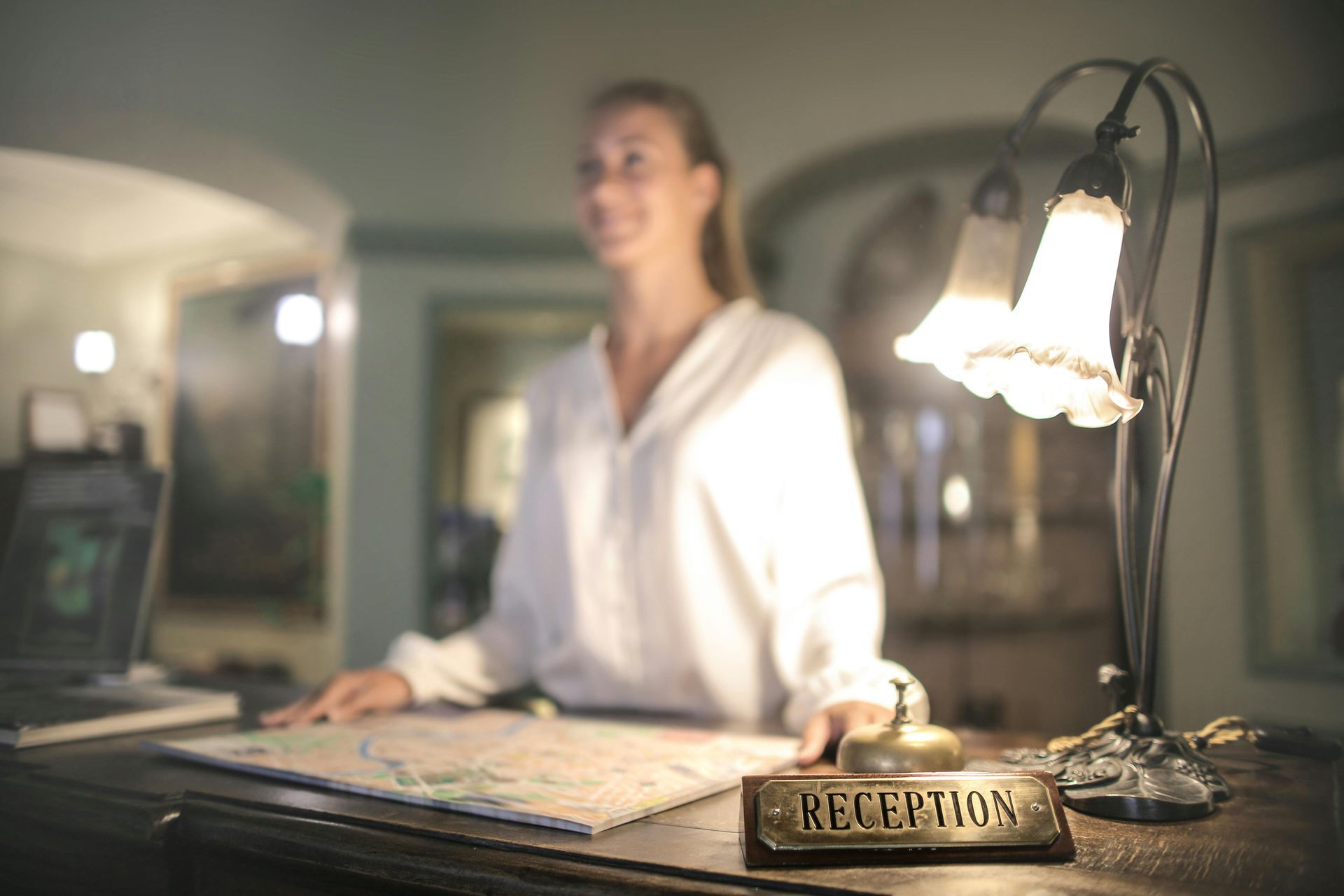 A woman is standing at a reception desk in a hotel.