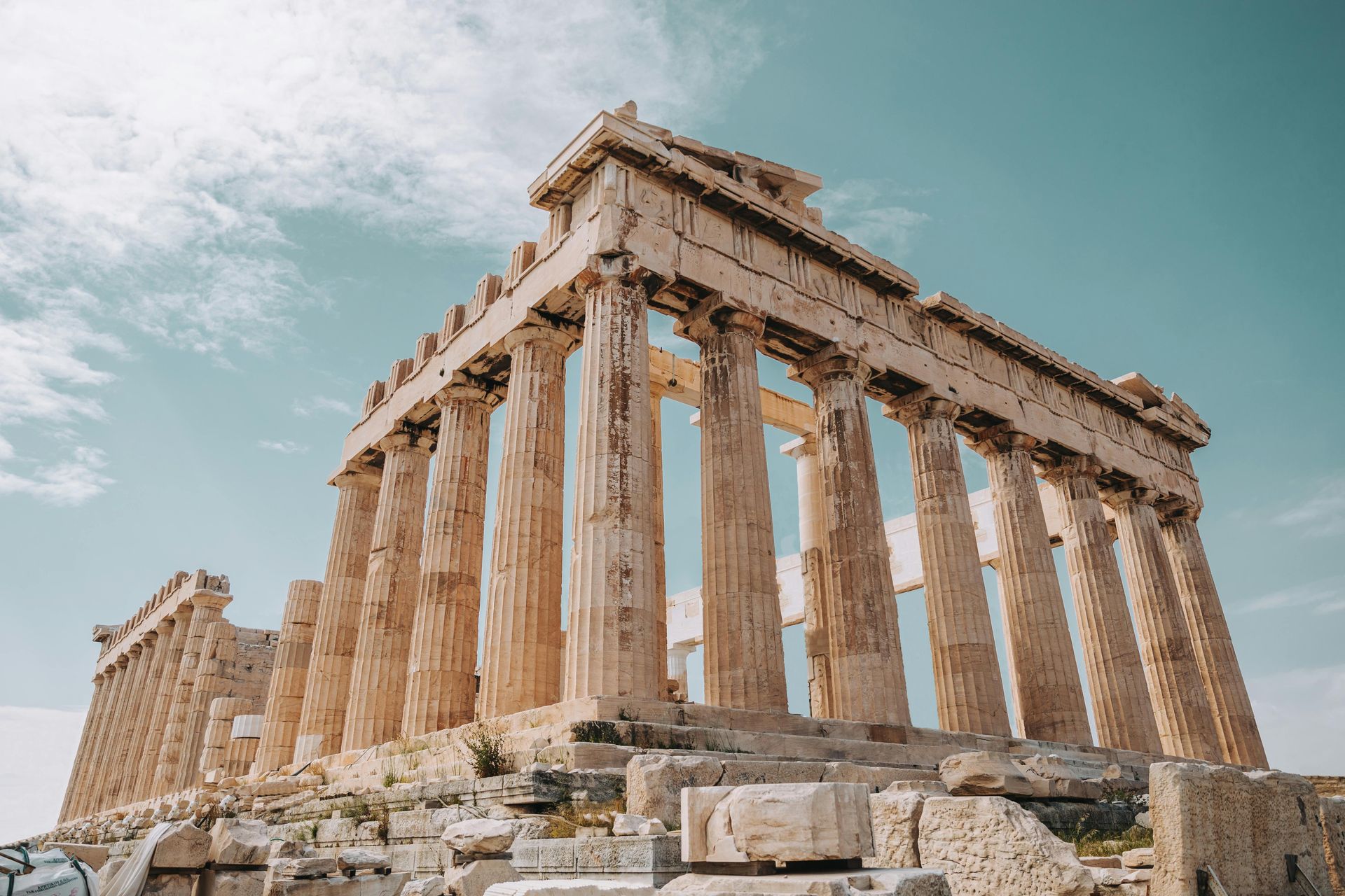 Parthenon temple ruins on a hill, Athens, Greece, with large Doric columns against a blue sky.