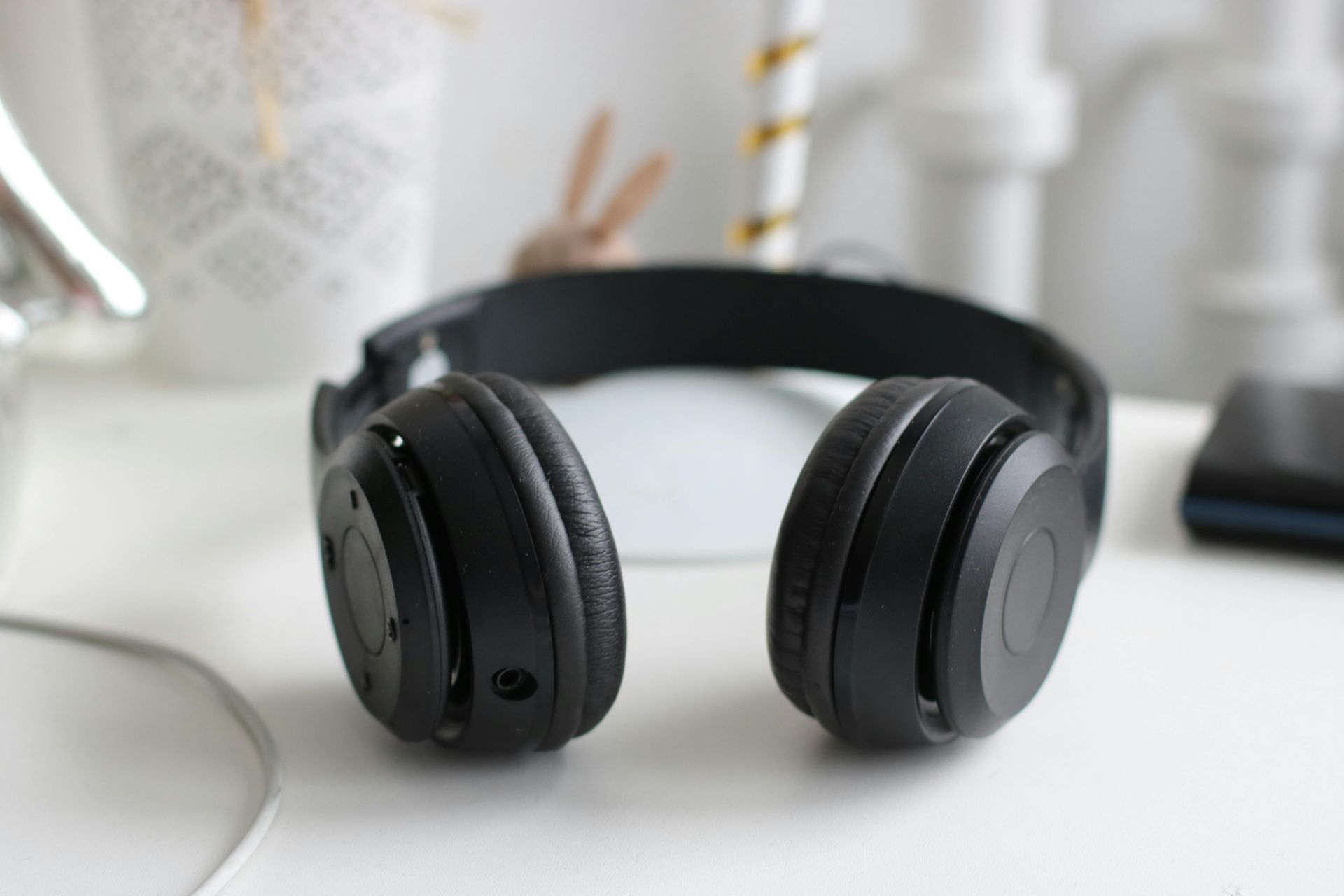 A pair of black headphones are sitting on a white table.