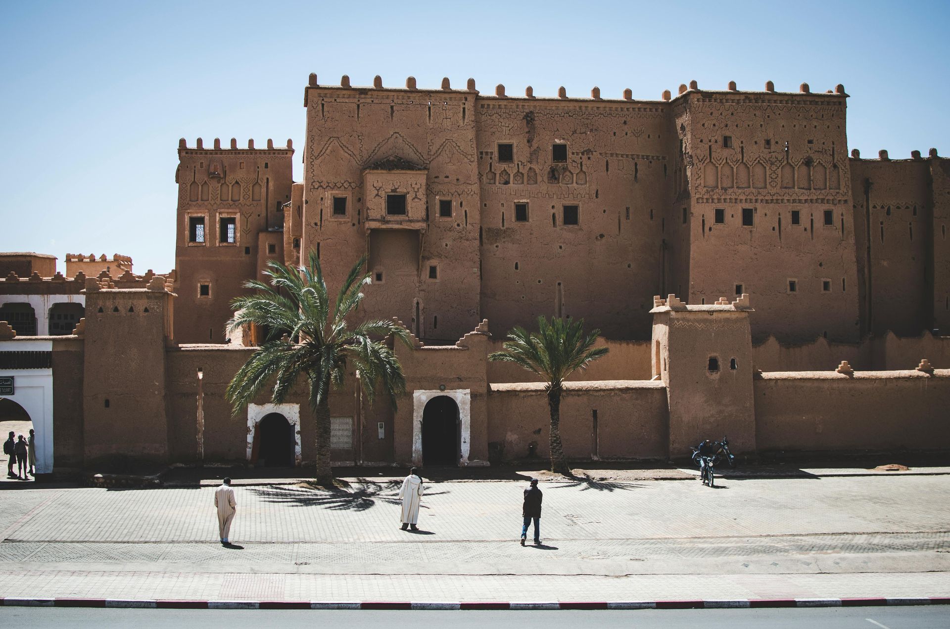 A group of people are walking in front of a large building