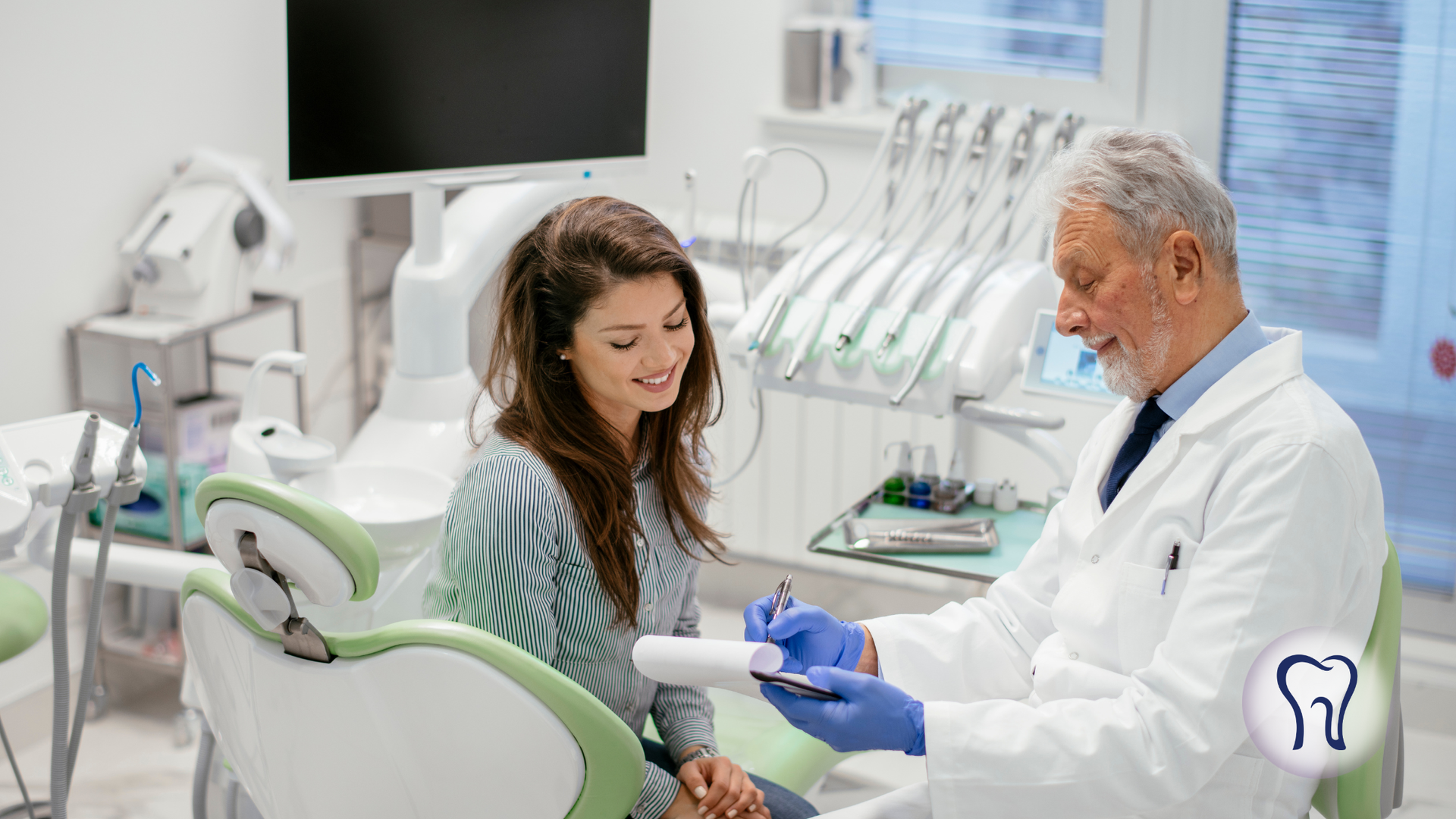 Dentist in lab coat reviewing paperwork with a patient in a dental chair.