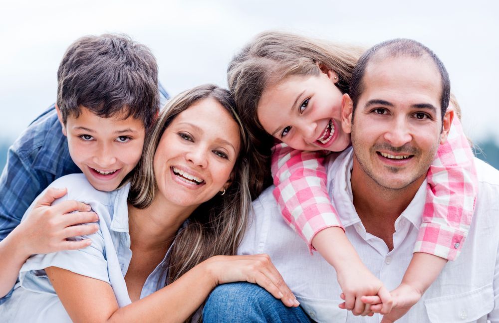 A family is posing for a picture together and smiling for the camera.