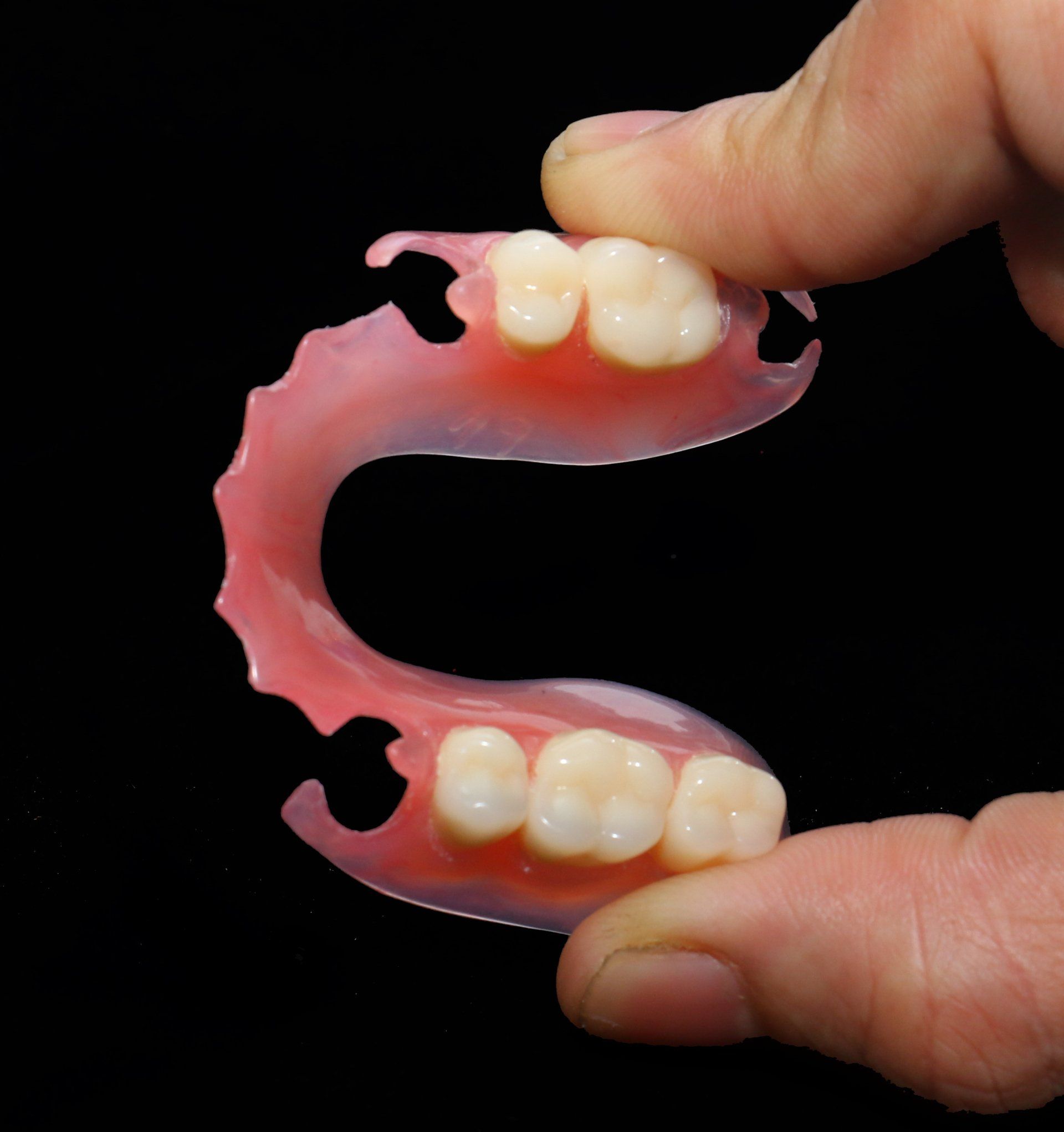 A person is holding a denture in their hand