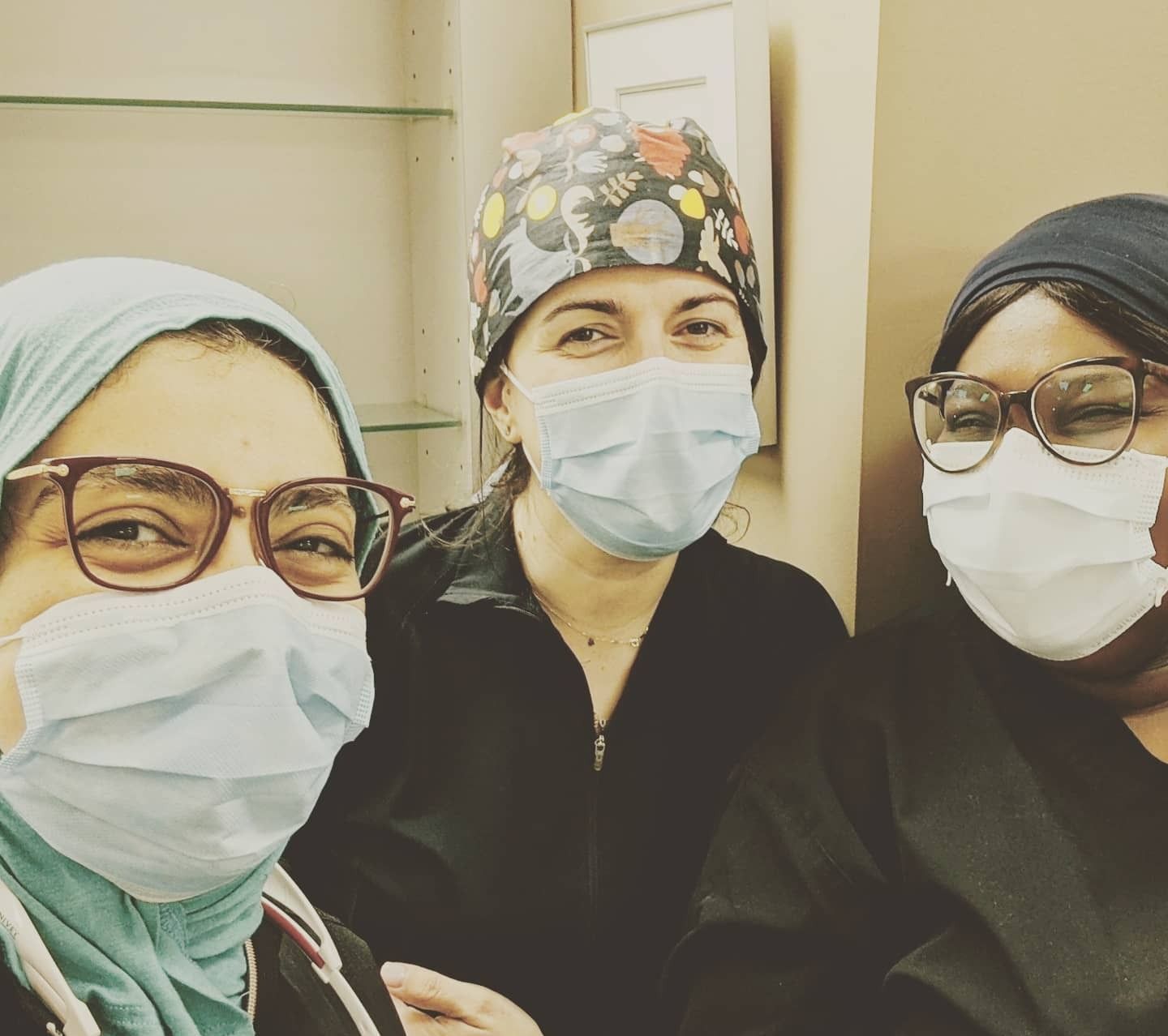 Three women wearing face masks and glasses are posing for a picture