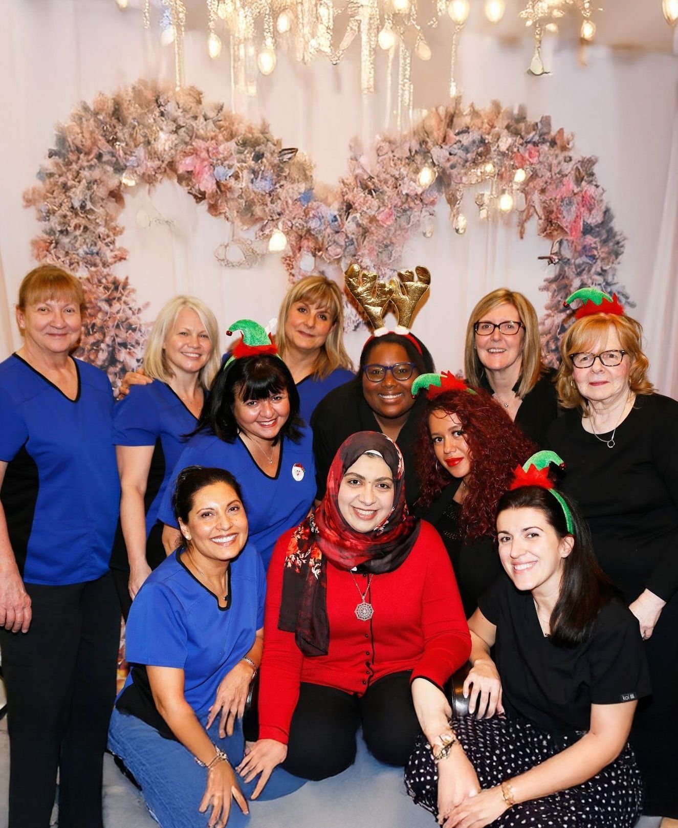 A group of women posing for a picture in front of a heart shaped wreath