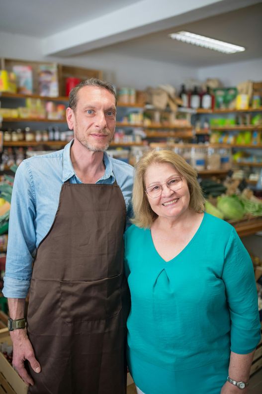 A man and a woman are posing for a picture in a grocery store.