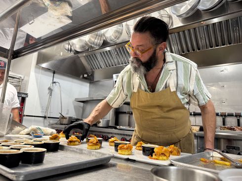 A man in an apron is preparing food in a kitchen.