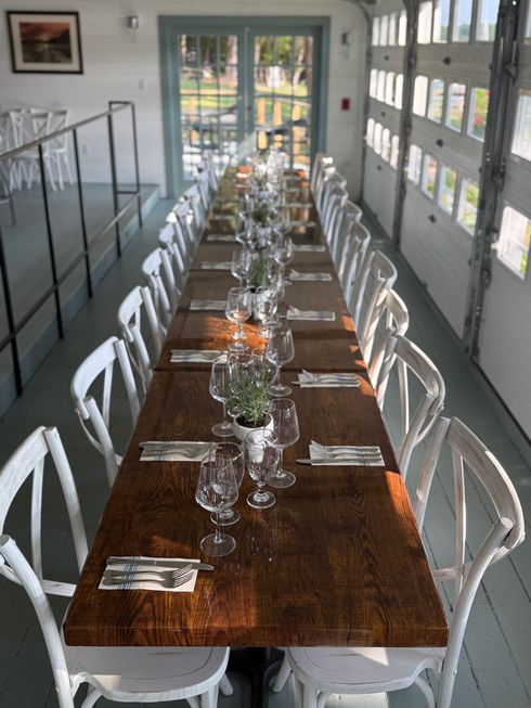 A long wooden table with white chairs in a room