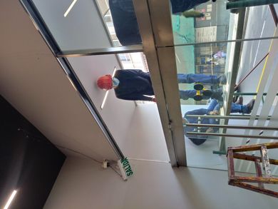 Primer plano de la fachada de un edificio moderno con paneles de vidrio reflectante enmarcados por una estructura reticular de acero gris.