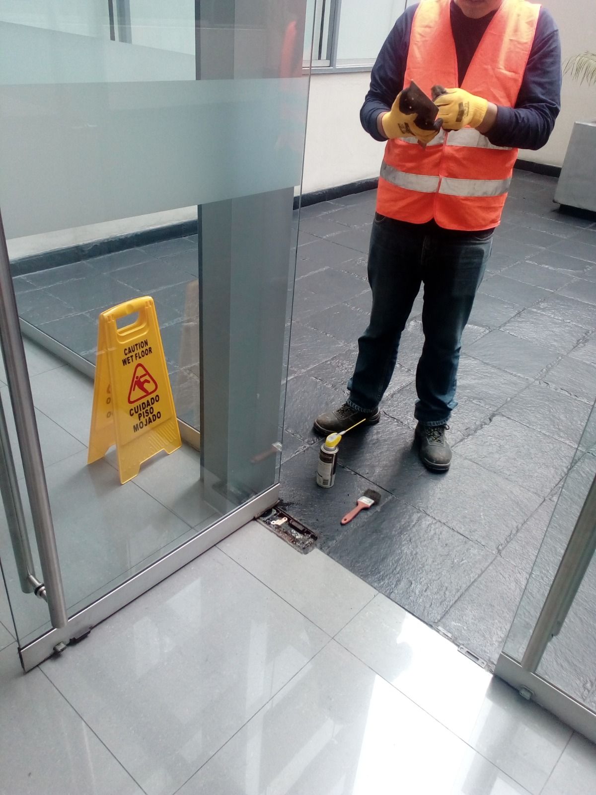 Un edificio de tres plantas de color amarillo brillante, con coloridas decoraciones florales y de colibríes en las paredes, y una entrada a pie de calle.