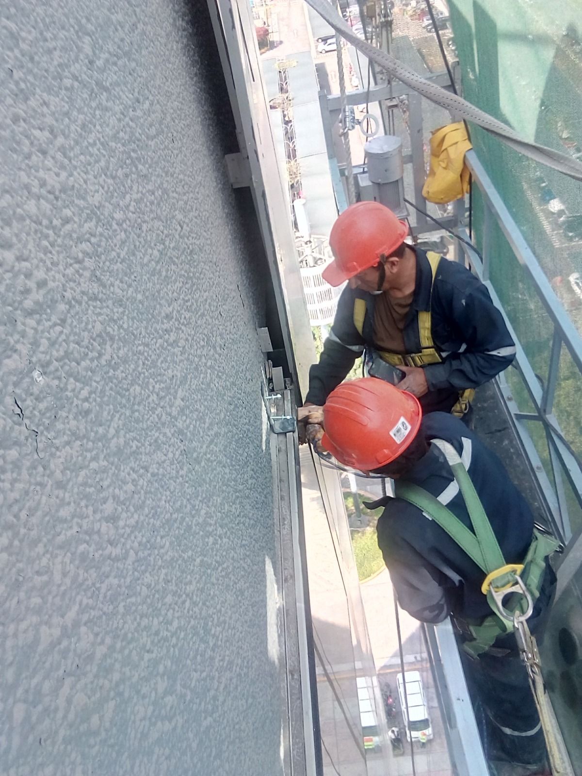 Un moderno edificio de varias plantas con fachada superior negra, grandes ventanales y un local comercial acristalado en la planta baja.