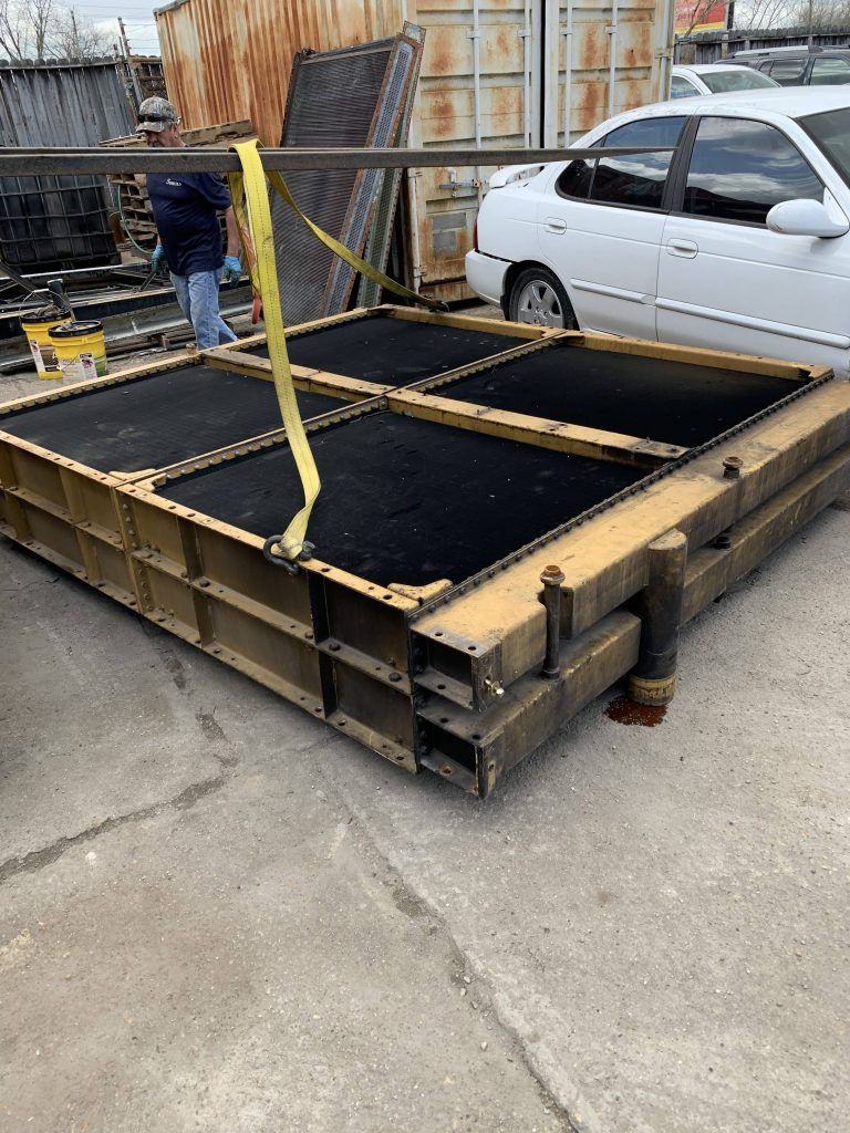 Large yellow radiator, black cooling elements, outdoors. A person handles a yellow strap.