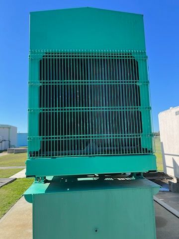 Large teal industrial cooling unit on a roof, with a grated front.