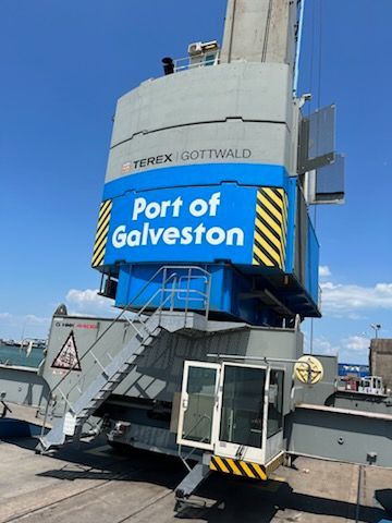 Large blue and gray crane at the Port of Galveston, under a bright blue sky.
