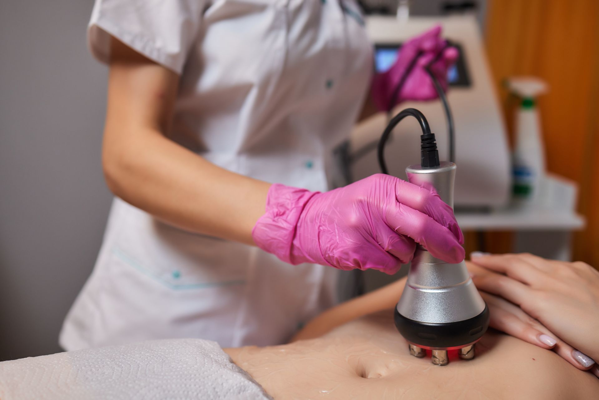 A woman is getting a cavitation treatment on her stomach.