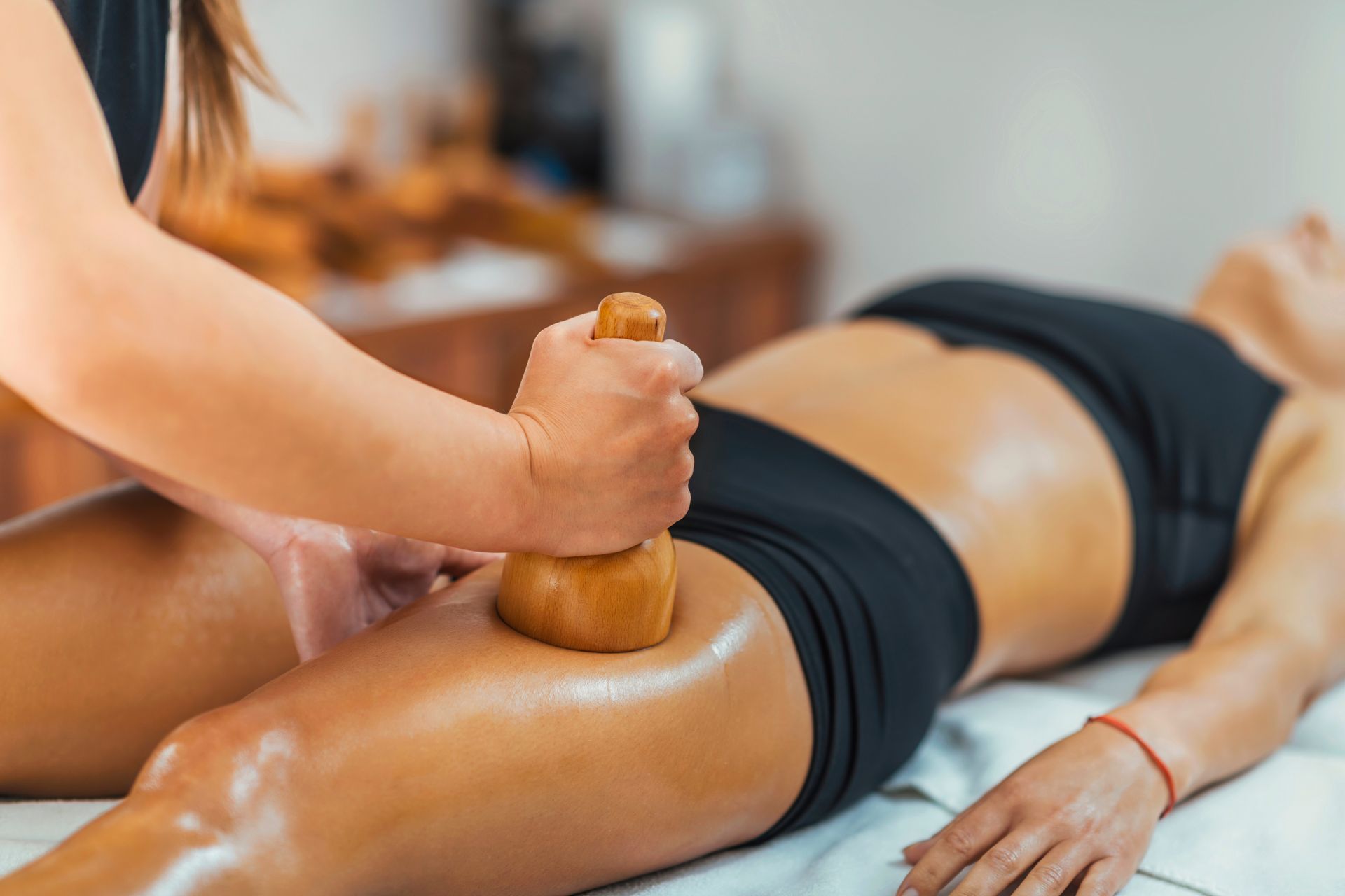 A woman is getting a wooden massage on her thigh.
