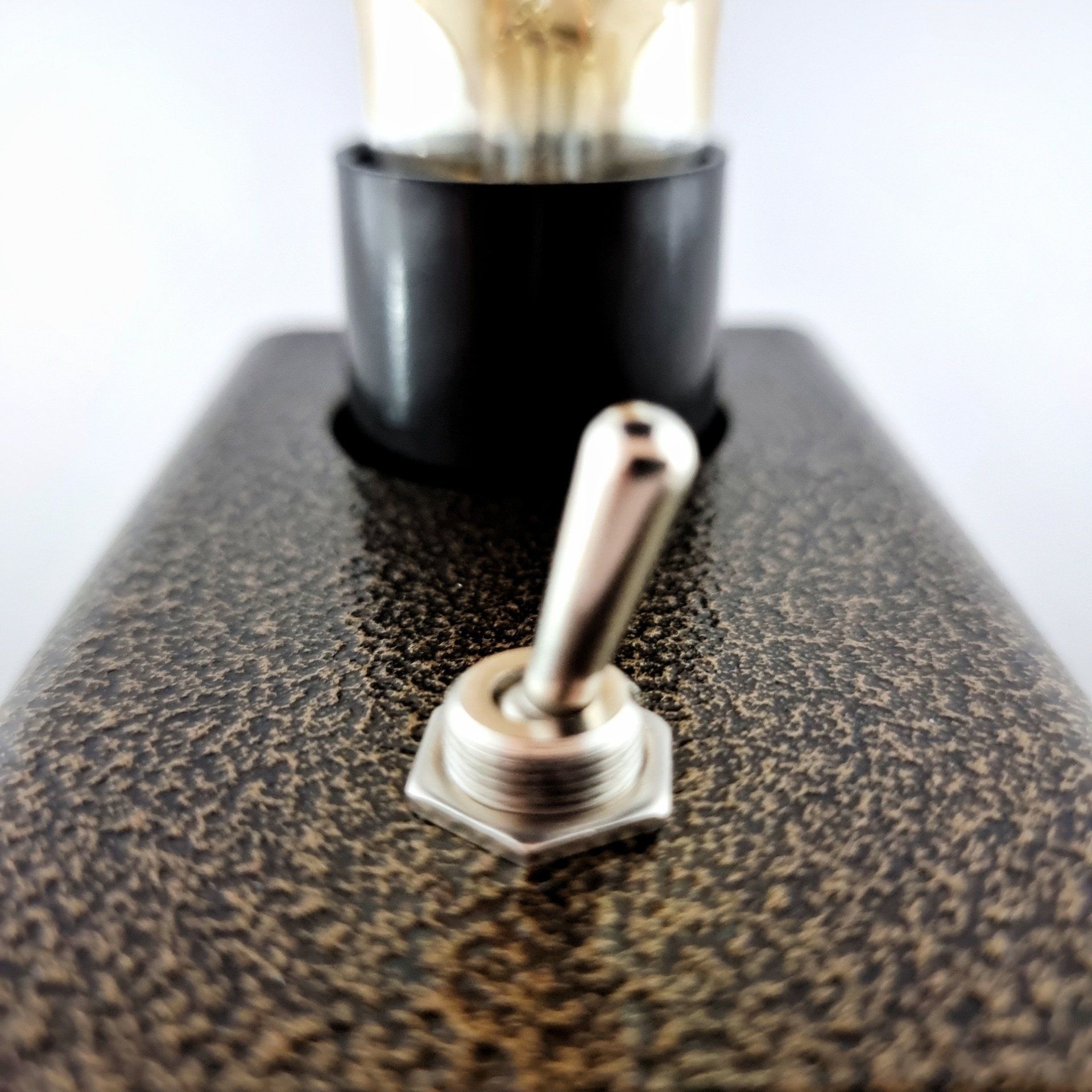 Een close-up van een tuimelschakelaar met een gloeilamp op de achtergrond