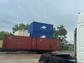 Two men shaking hands in front of a storage container with 
