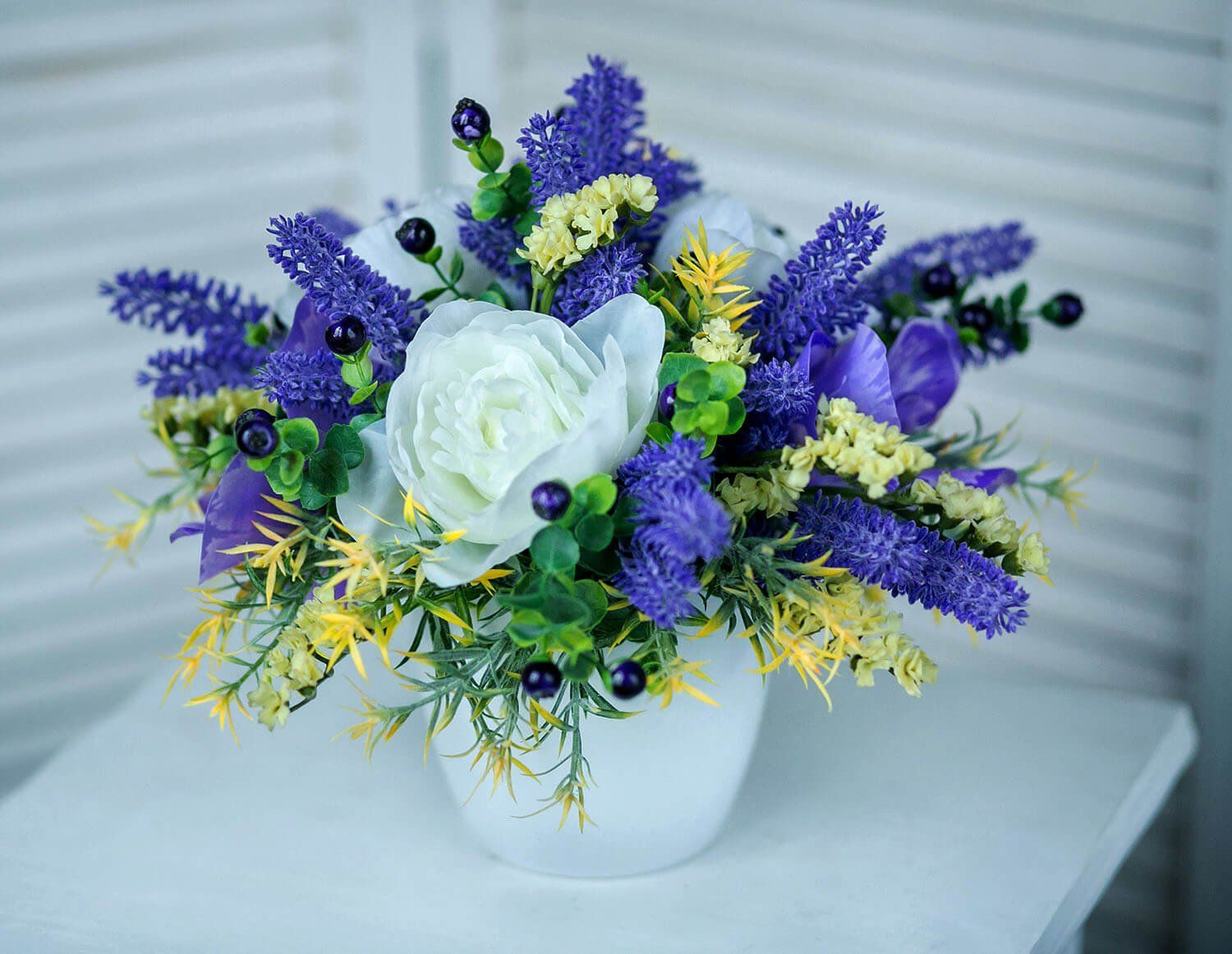 A vase filled with purple and yellow flowers is sitting on a table.