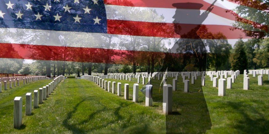 An american flag is flying over a cemetery with graves.