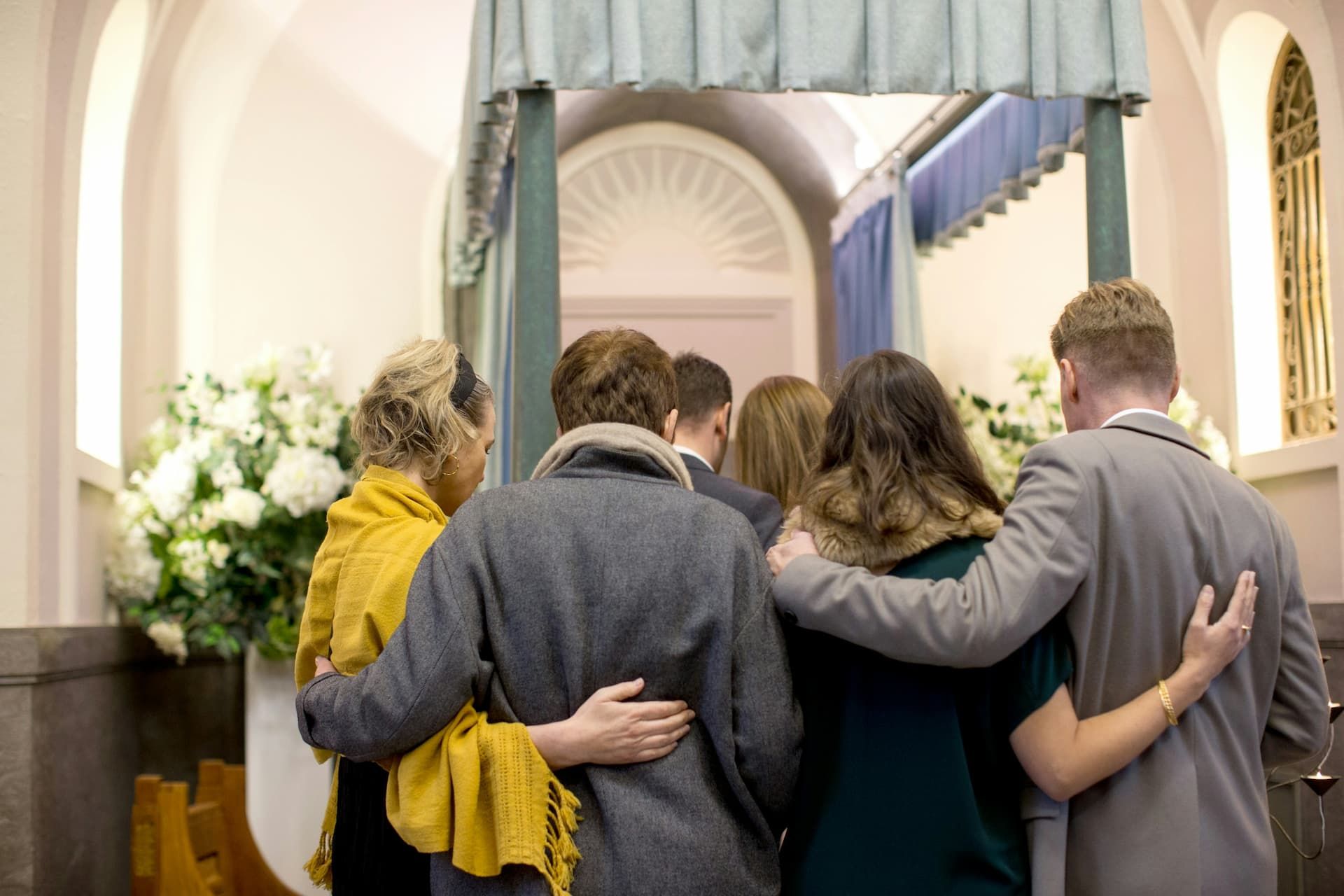 A group of people are standing in a church hugging each other.